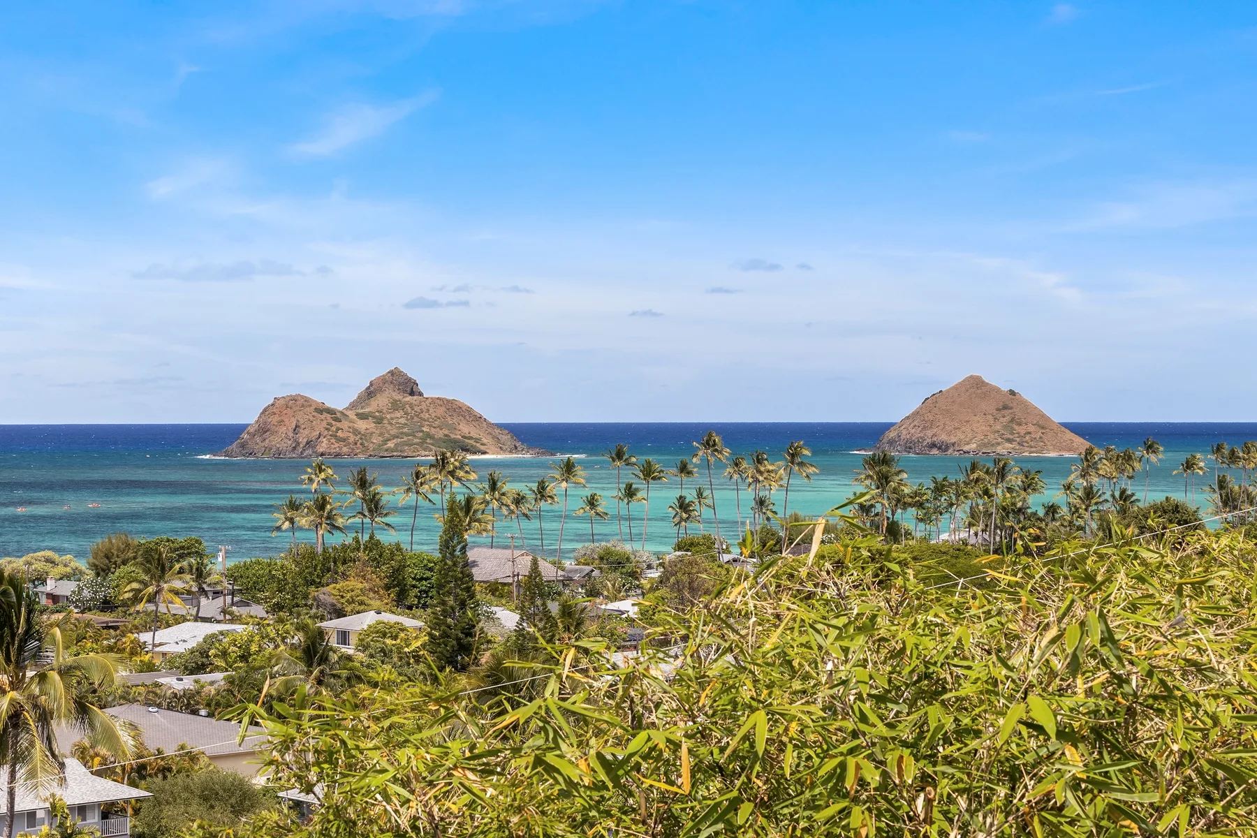 Paisaje costero con palmeras, aguas turquesas y dos islotes rocosos.
