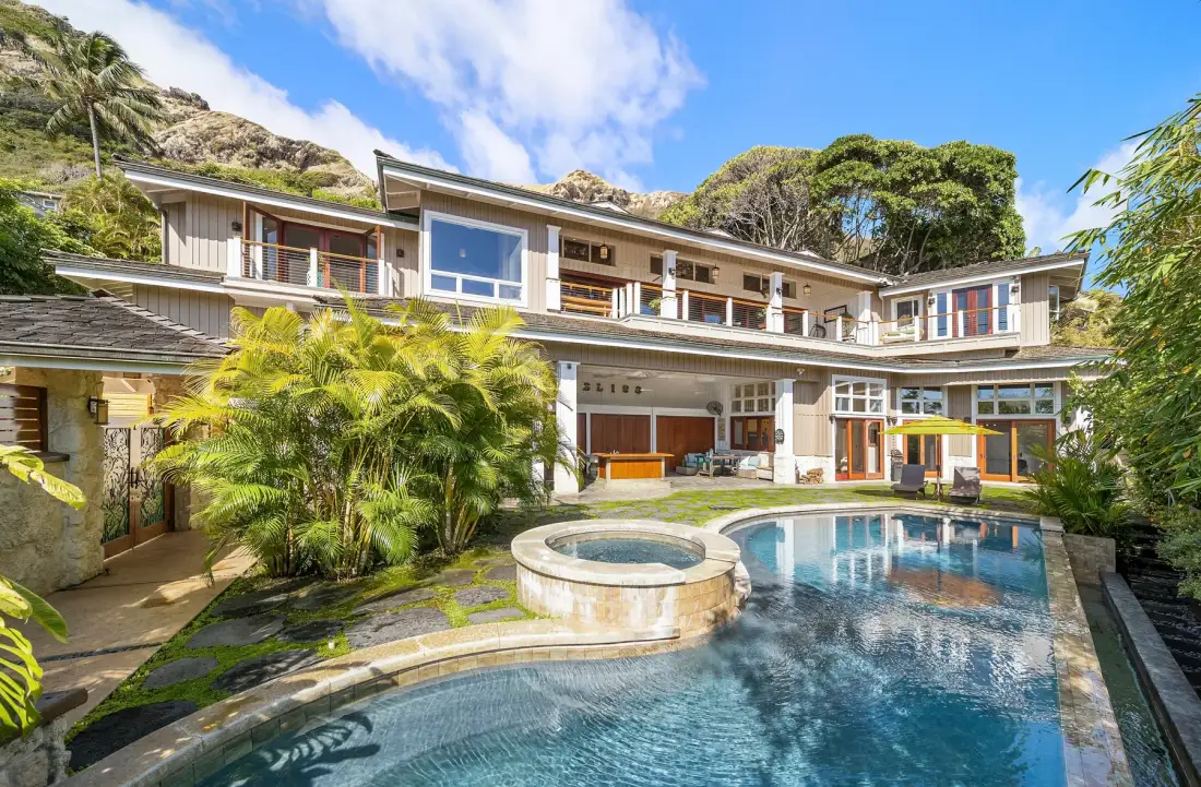Una piscina y un spa circular se encuentran junto a una casa moderna de varios niveles.