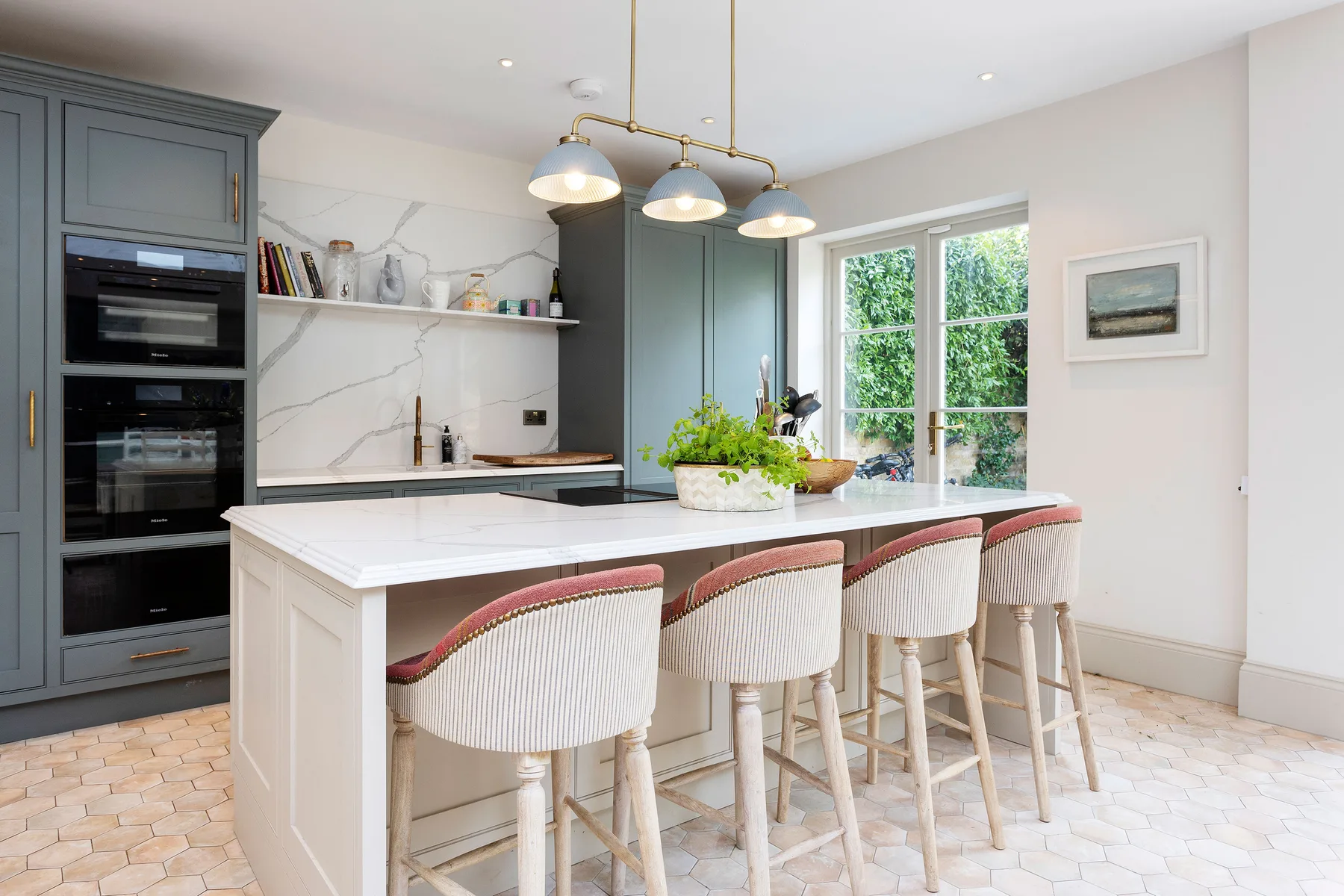 A bright kitchen with a white island and upholstered bar seating.