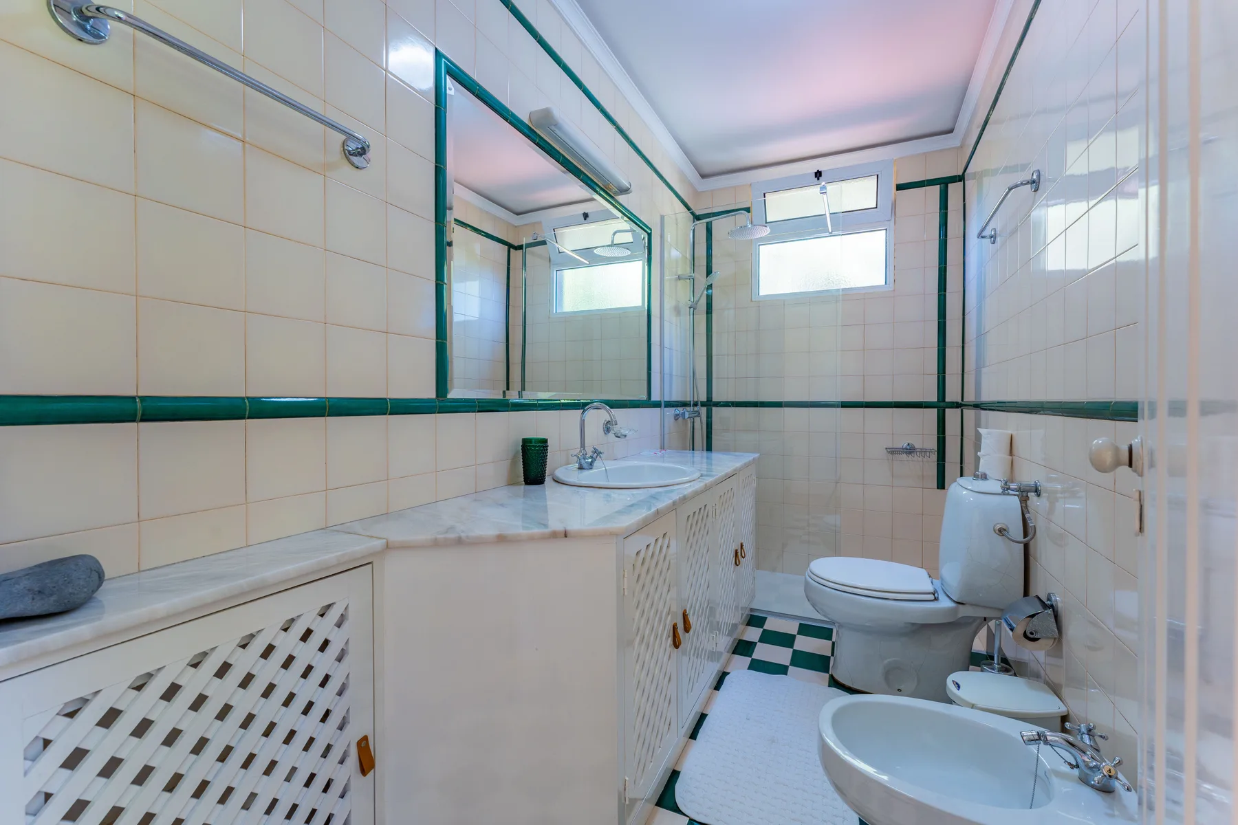 Un baño con azulejos, lavabo, inodoro y bidé.