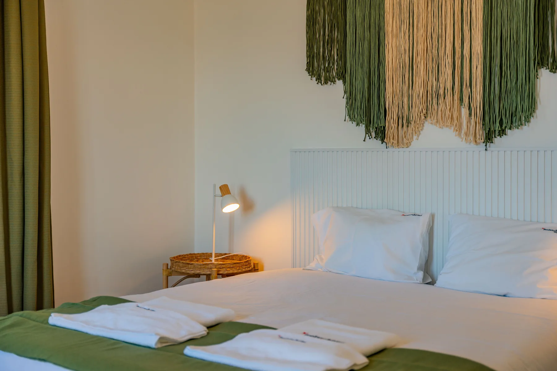 Un dormitorio con una cama bien tendida y una pequeña lámpara de noche.