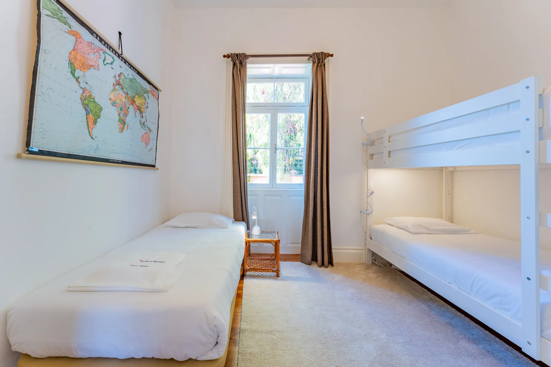 Un dormitorio con una cama individual y una litera blanca junto a una ventana.