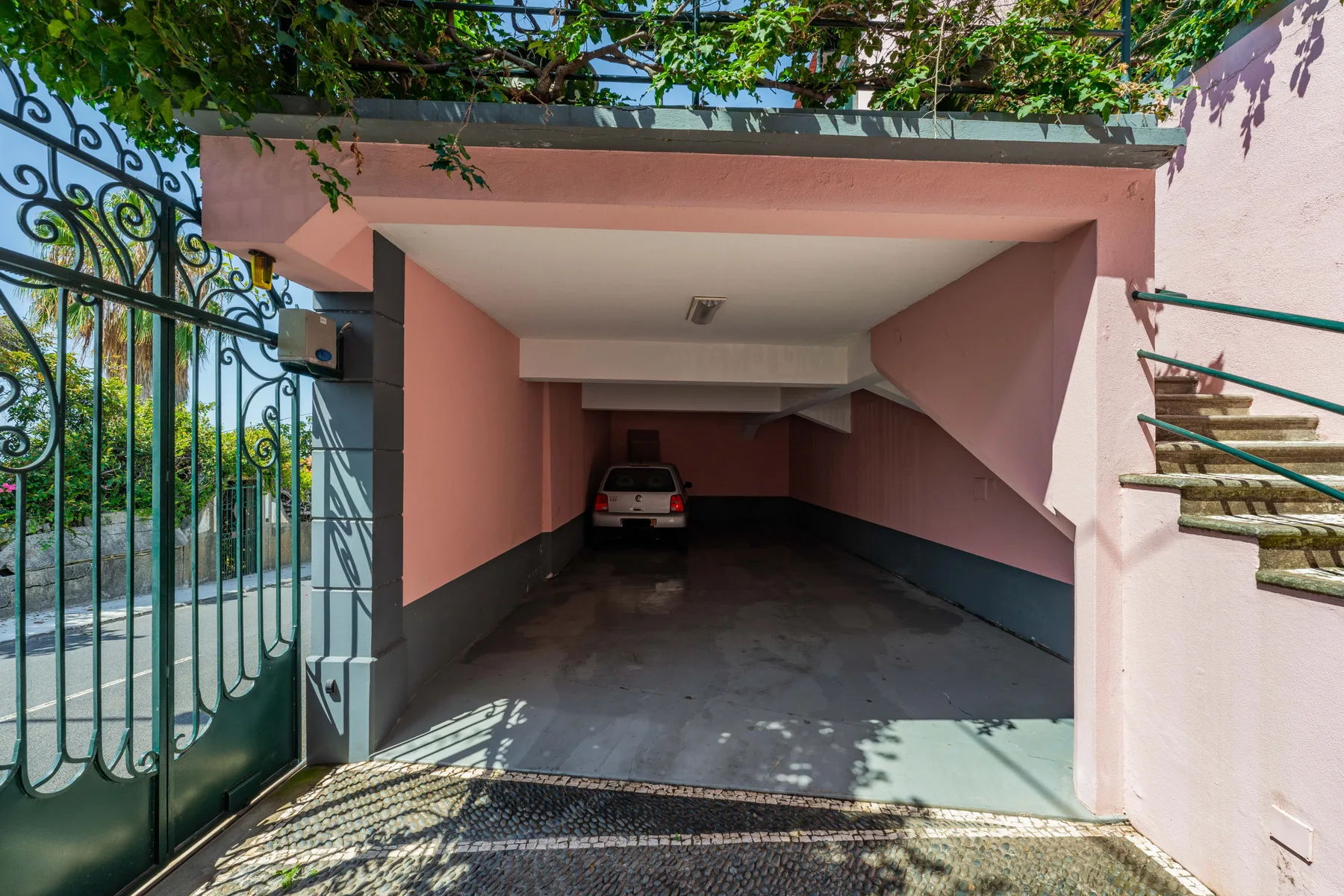 Se ve una zona de estacionamiento cubierta con un automóvil detrás de una puerta metálica abierta.