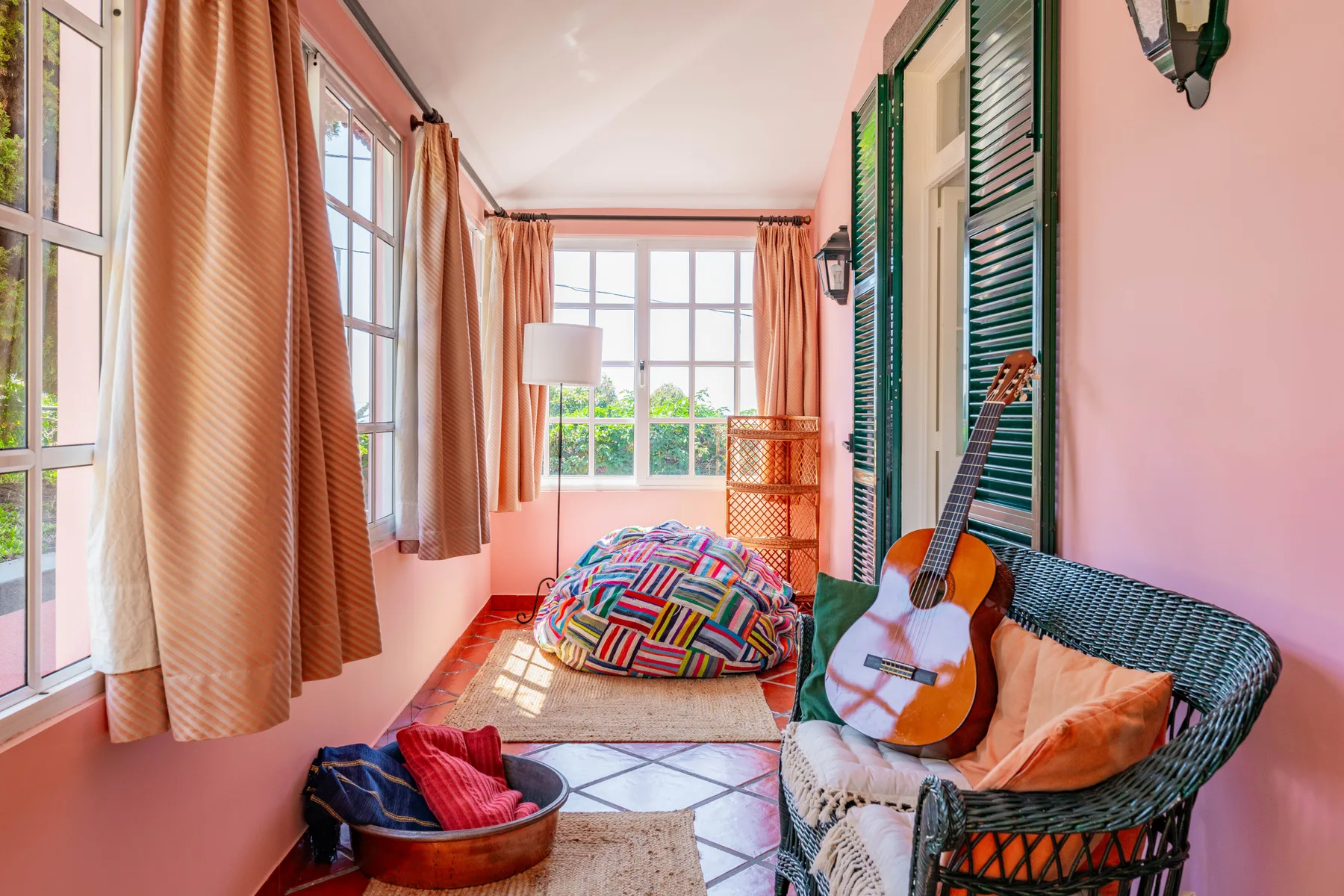 Una luminosa zona de estar con cojines coloridos y una guitarra junto a la ventana.
