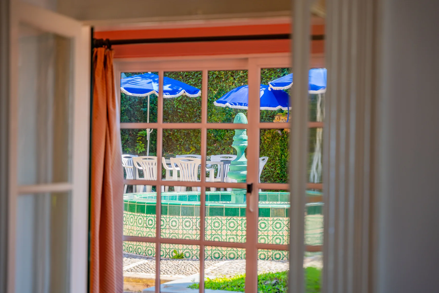 Vista a través de puertas de vidrio hacia una piscina exterior y un patio.