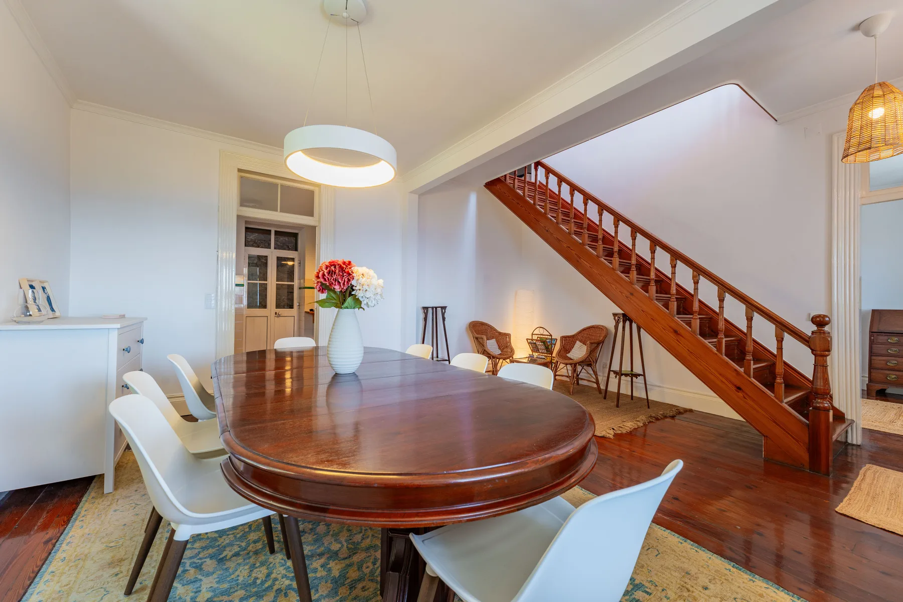 Un comedor con una gran mesa de madera junto a una escalera.