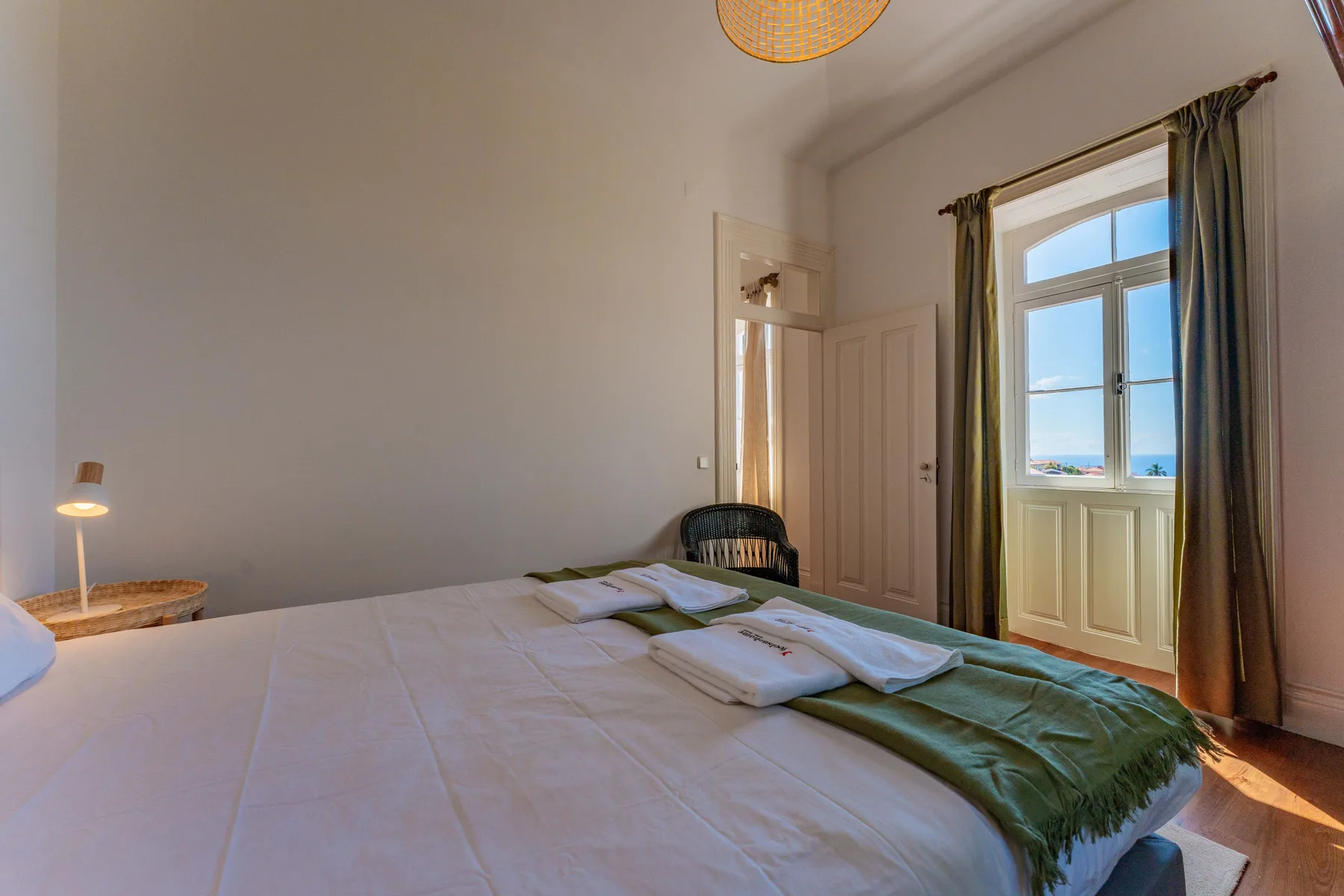 Un dormitorio con la cama tendida y una ventana con vistas al agua.
