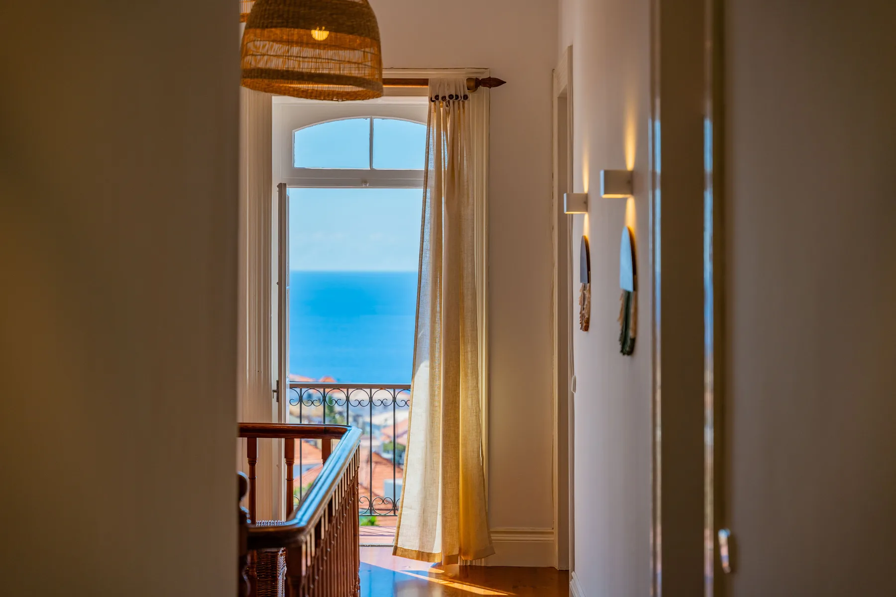 Un pasillo luminoso da a una ventana alta con vistas al mar.