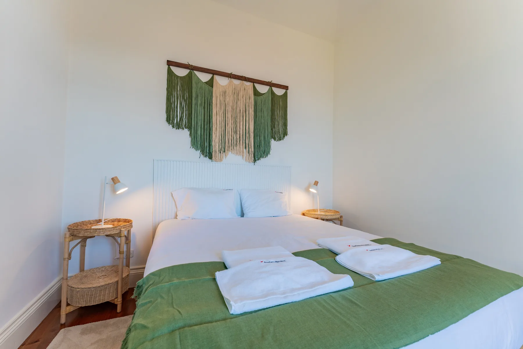 Un dormitorio con una cama vestida de blanco y verde.