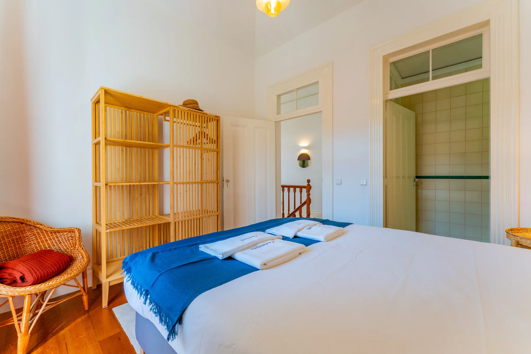 Un dormitorio con una cama cubierta de ropa de cama blanca y una manta azul.