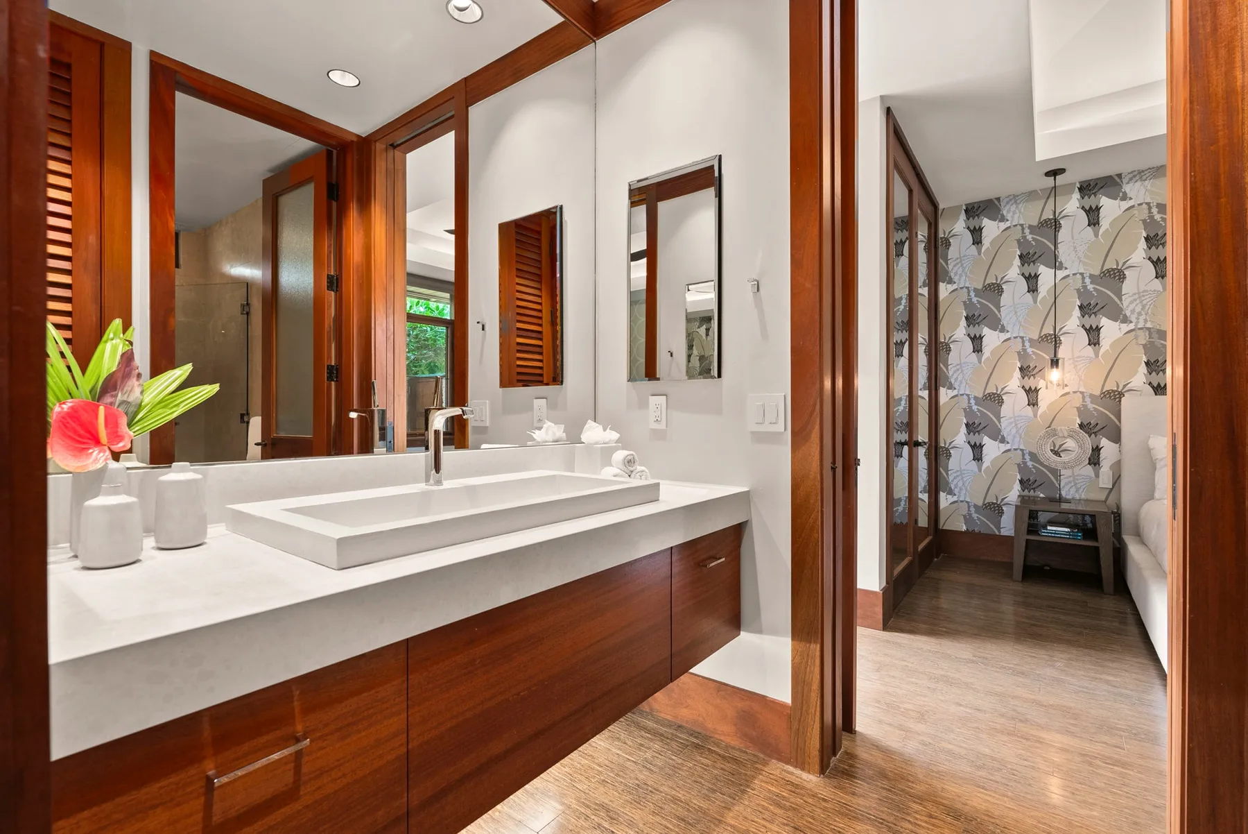 Un lavabo de baño con un espejo amplio y una puerta abierta hacia una zona de ducha con azulejos.