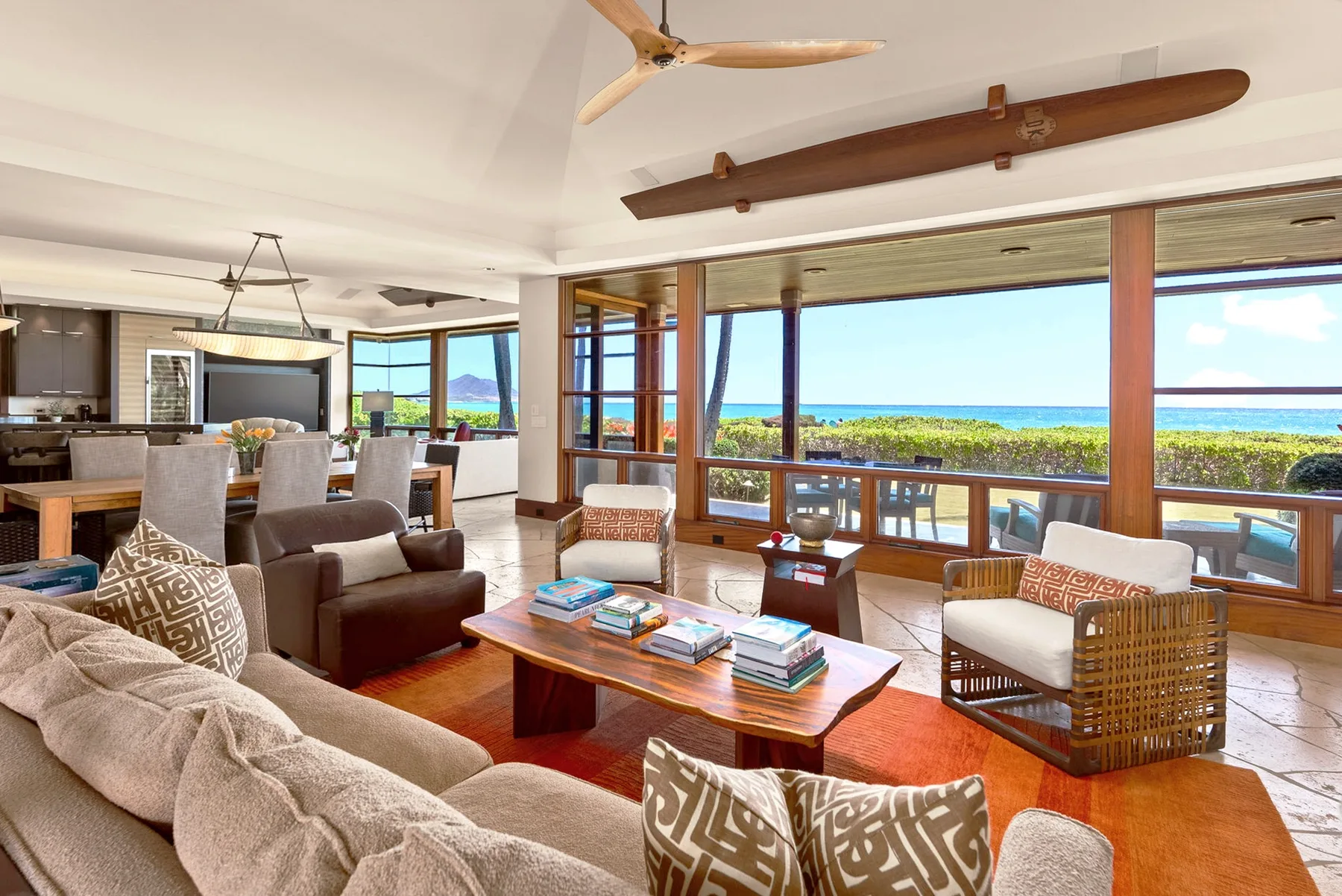 Una sala luminosa con asientos, una mesa de centro y vistas al mar por grandes ventanas.