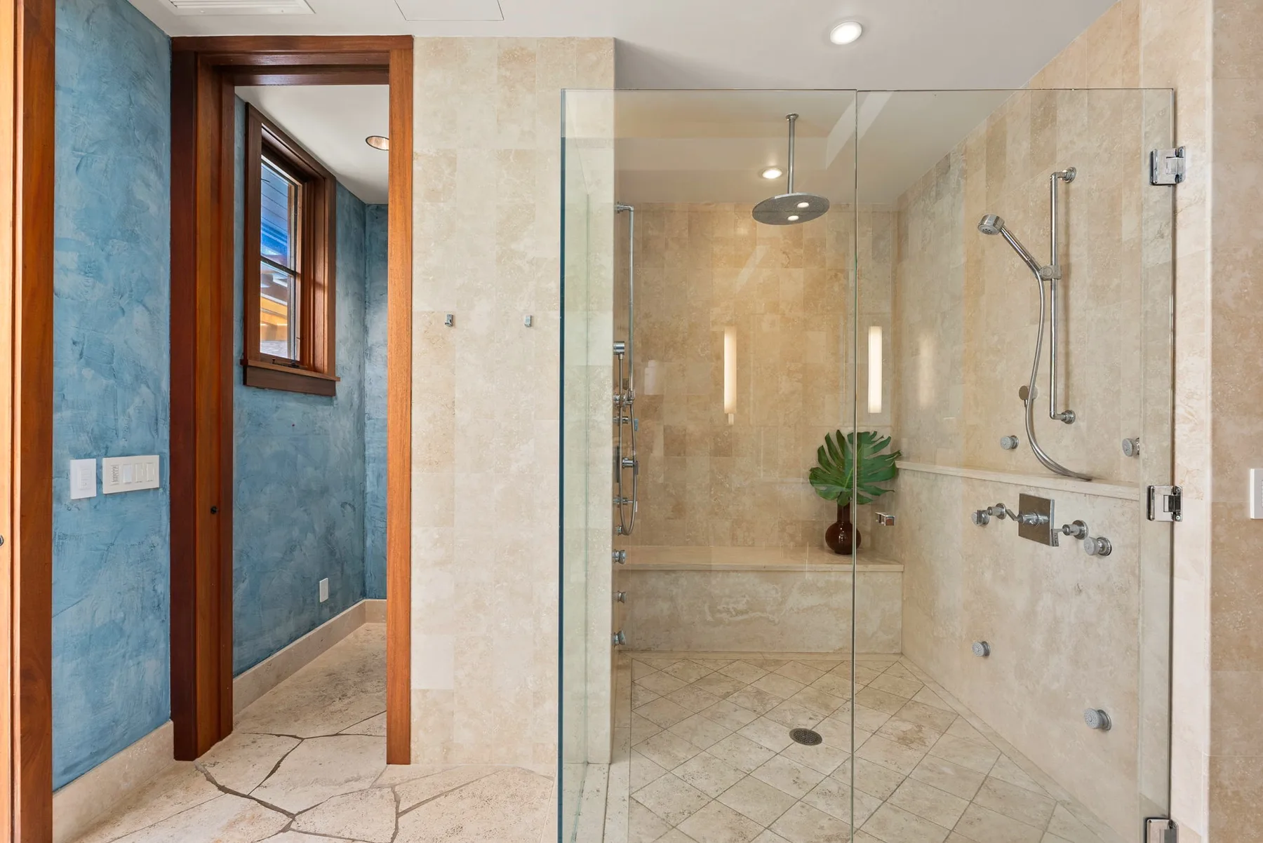 Baño con azulejos, ducha de vidrio y una ventana en el área contigua.