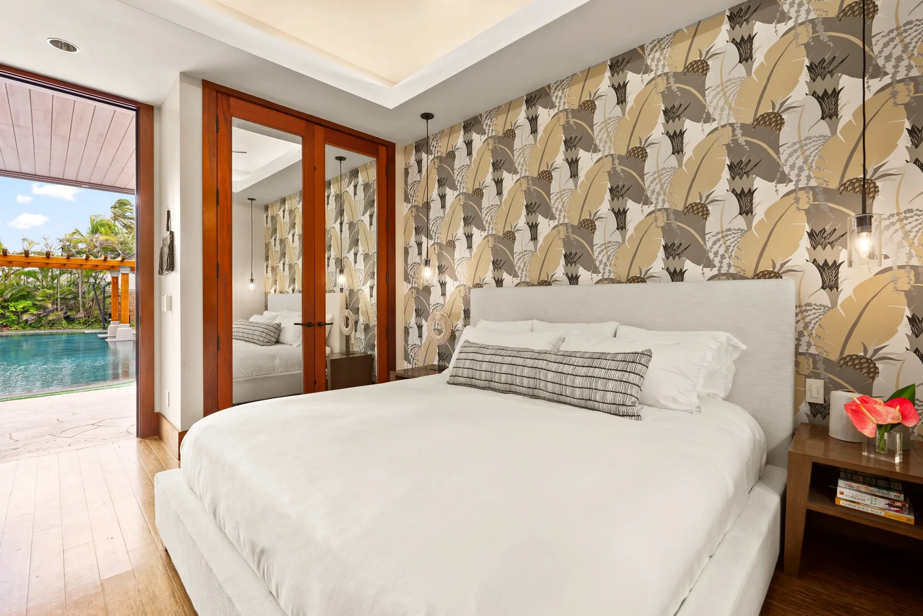 Dormitorio con una cama blanca y papel tapiz estampado.