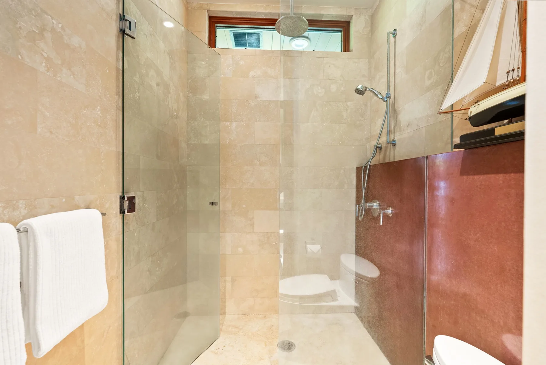 Un baño revestido de azulejos con una ducha de vidrio y un cabezal en la pared.