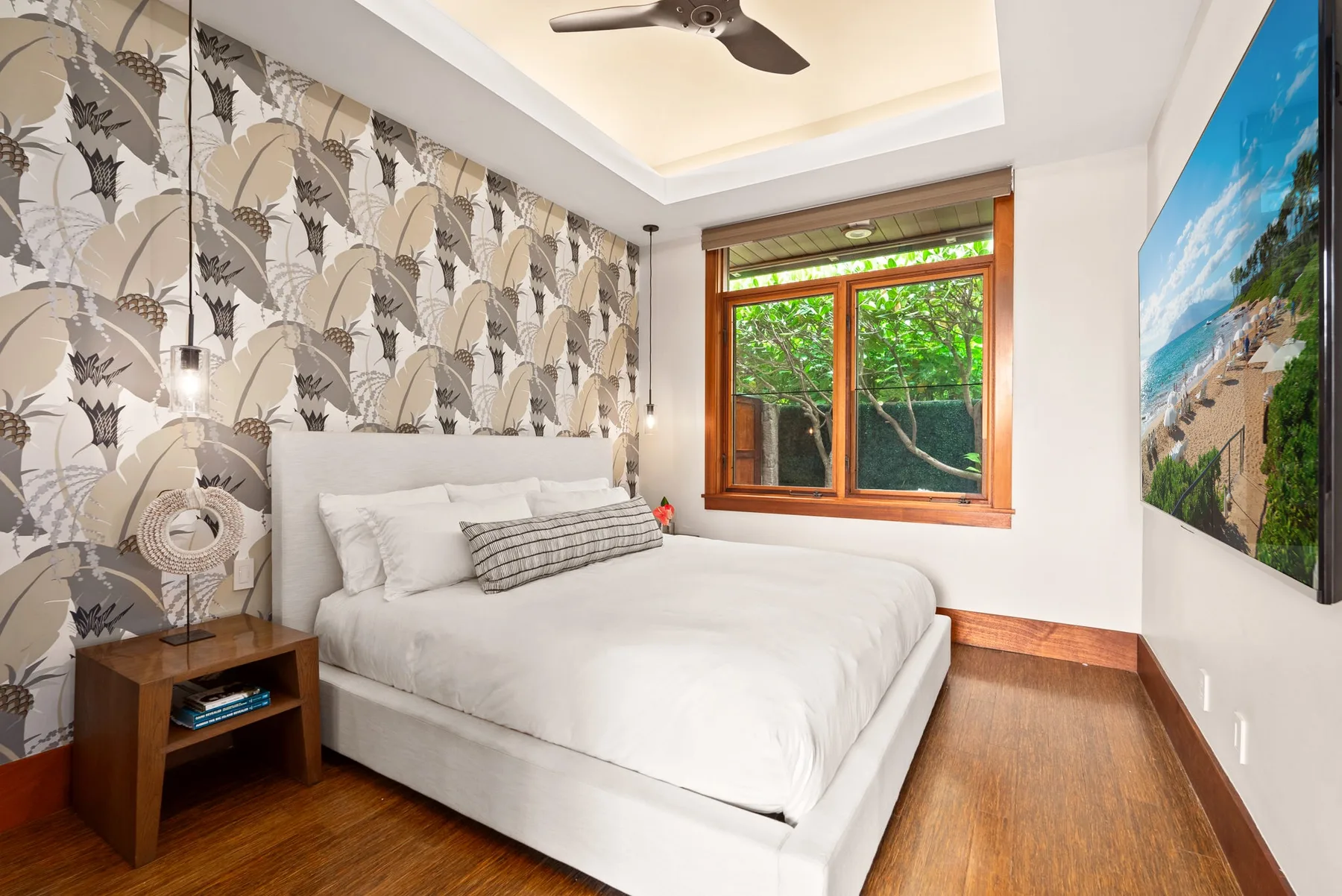 Dormitorio con una cama blanca, papel tapiz estampado y una ventana con marco de madera.