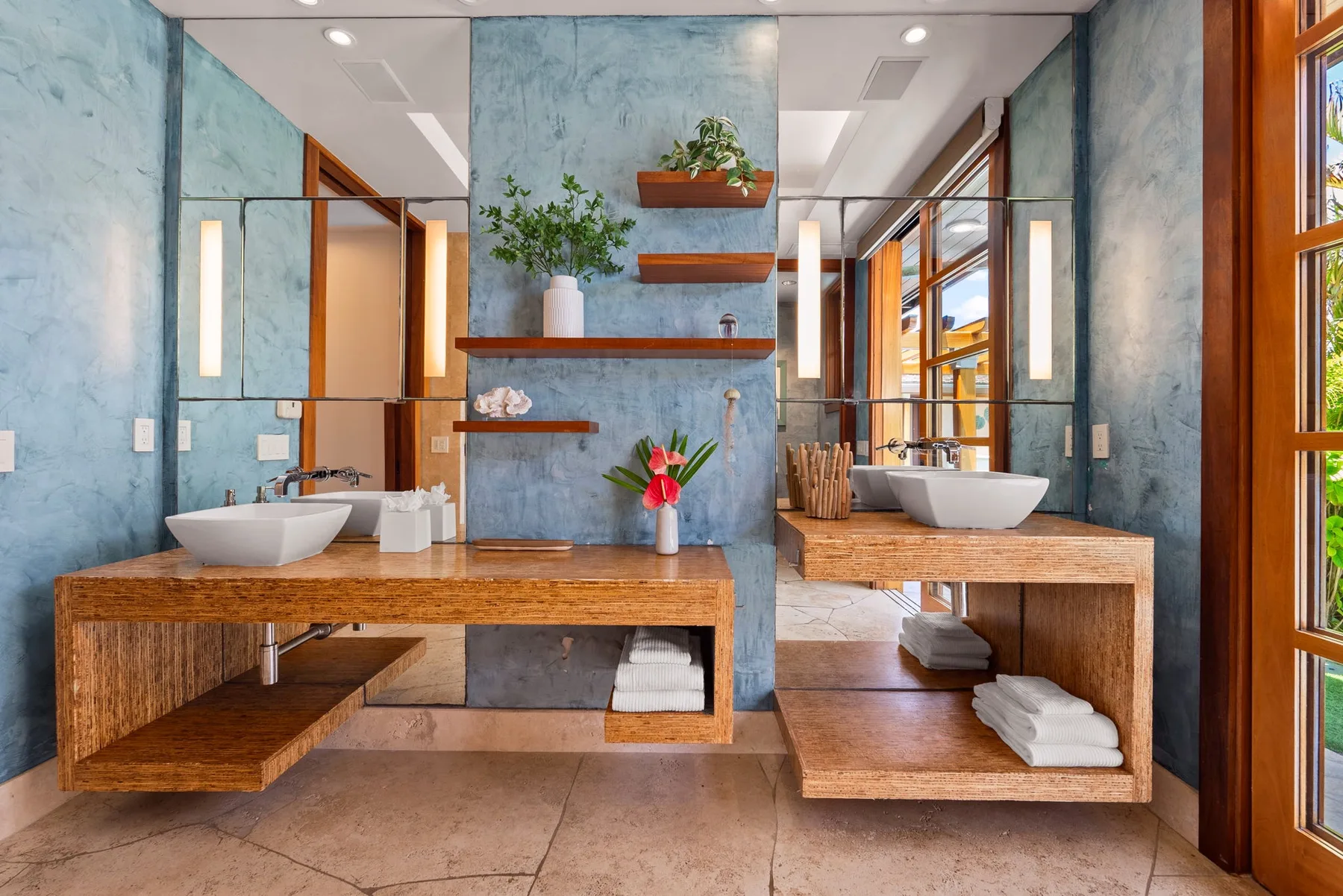Un baño con dos lavabos, encimeras de madera, espejos y paredes azules.