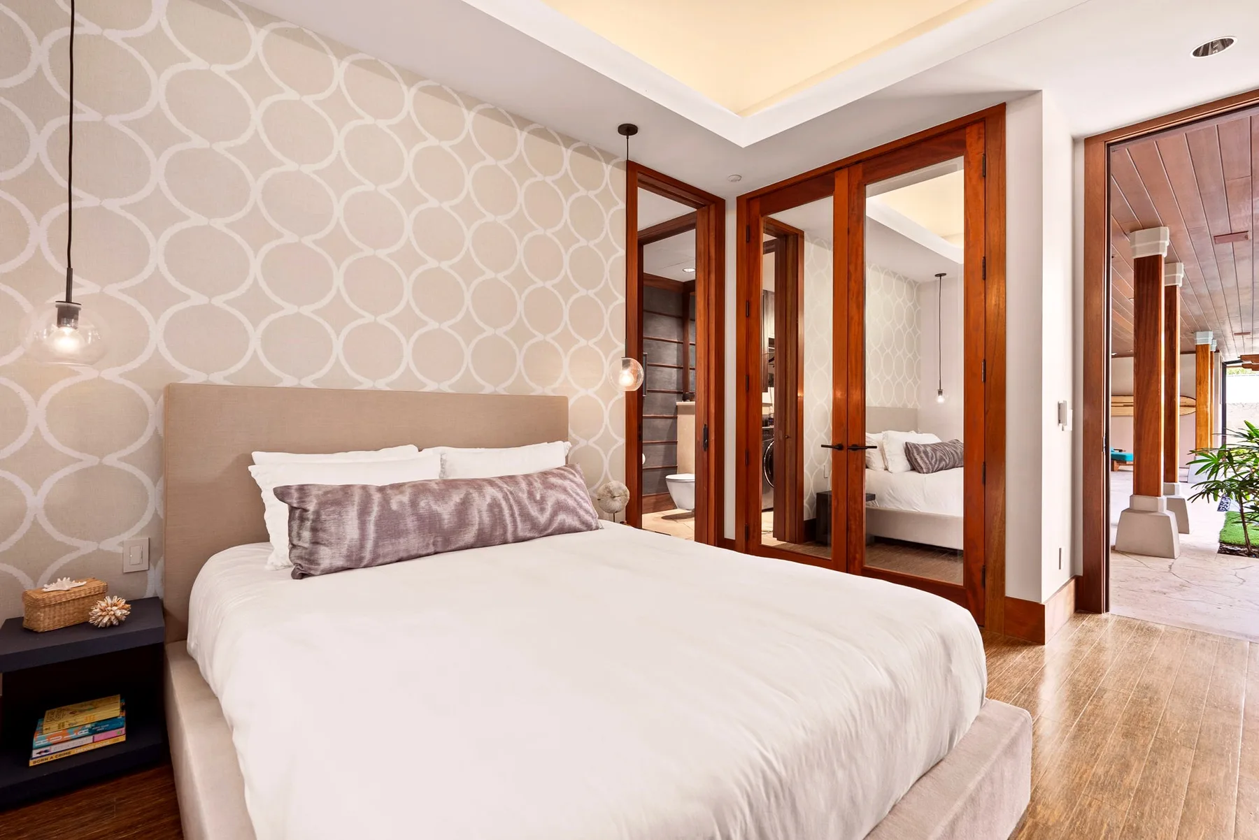 Un dormitorio con una cama bien tendida y puertas espejadas con marco de madera.