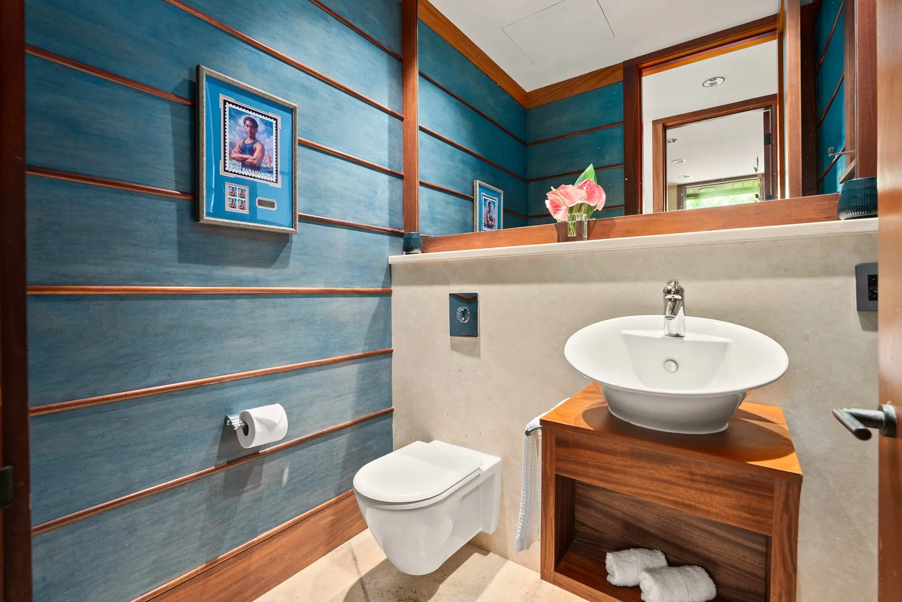 Un baño con un lavabo sobre una encimera de madera y paneles azules en la pared.