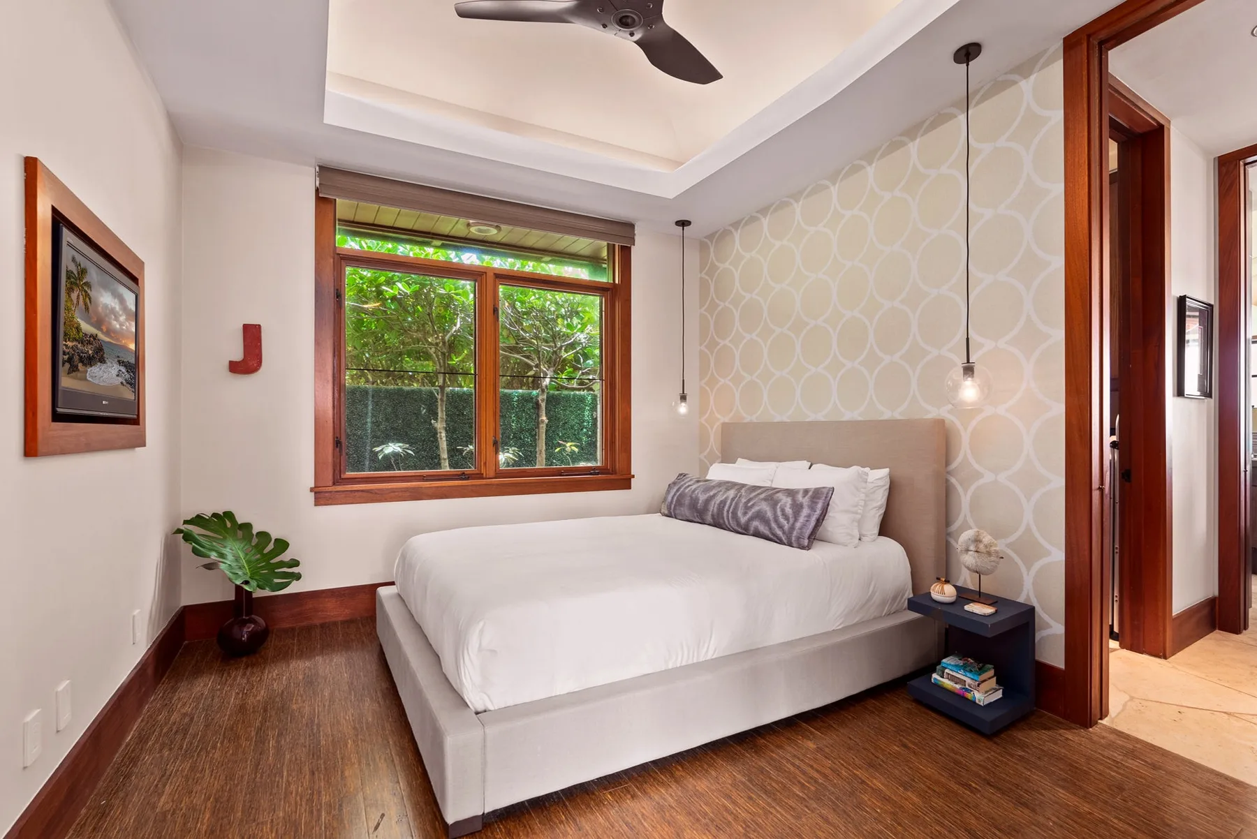 Un dormitorio con una cama junto a una ventana con vegetación frondosa.