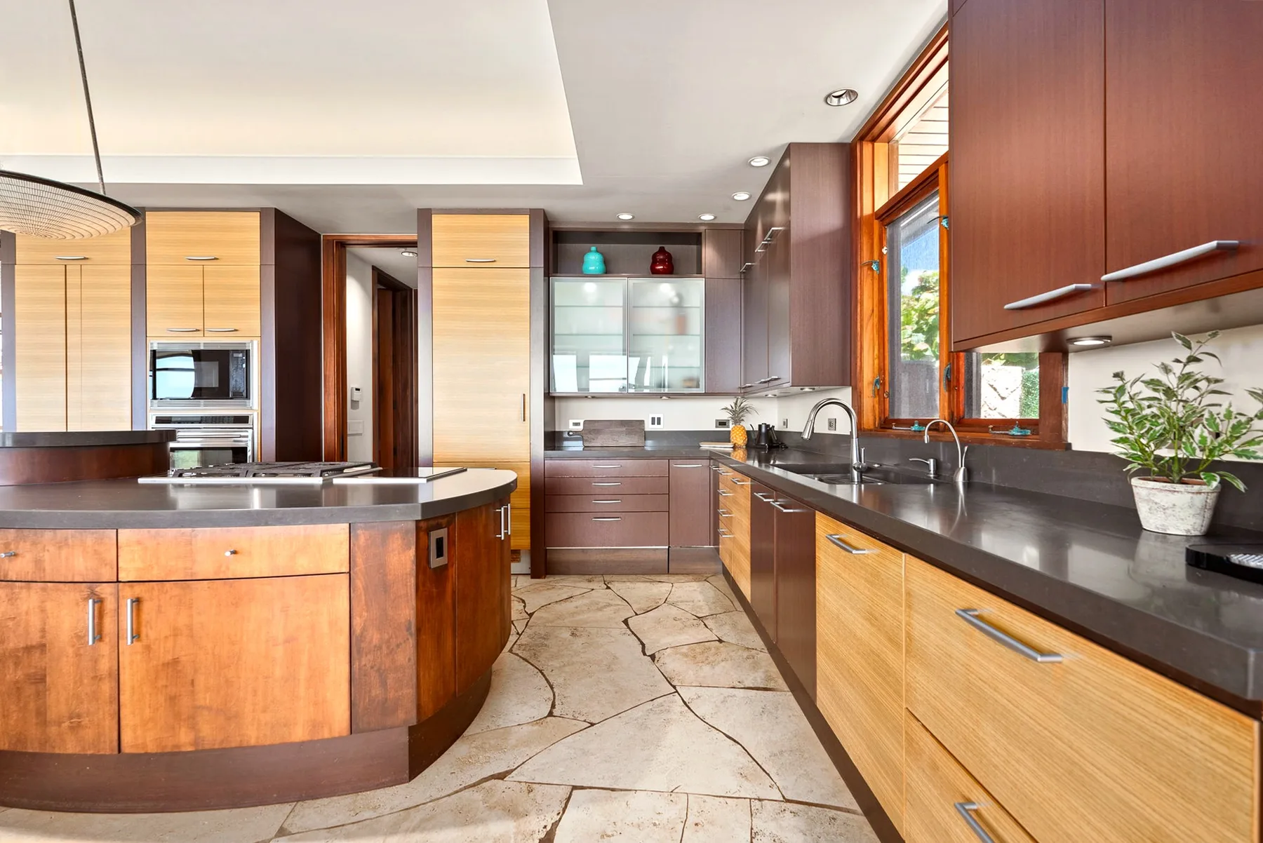 Una cocina moderna con gabinetes de madera, encimeras oscuras y una isla central.
