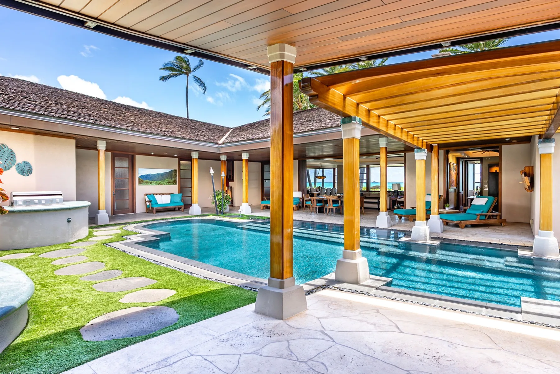 Una zona de piscina exterior cubierta, con agua turquesa y asientos bajo una pérgola de madera.