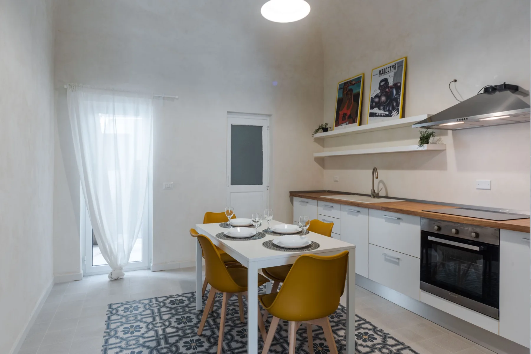 Comedor junto a una cocina compacta, con la mesa puesta y asientos amarillos.
