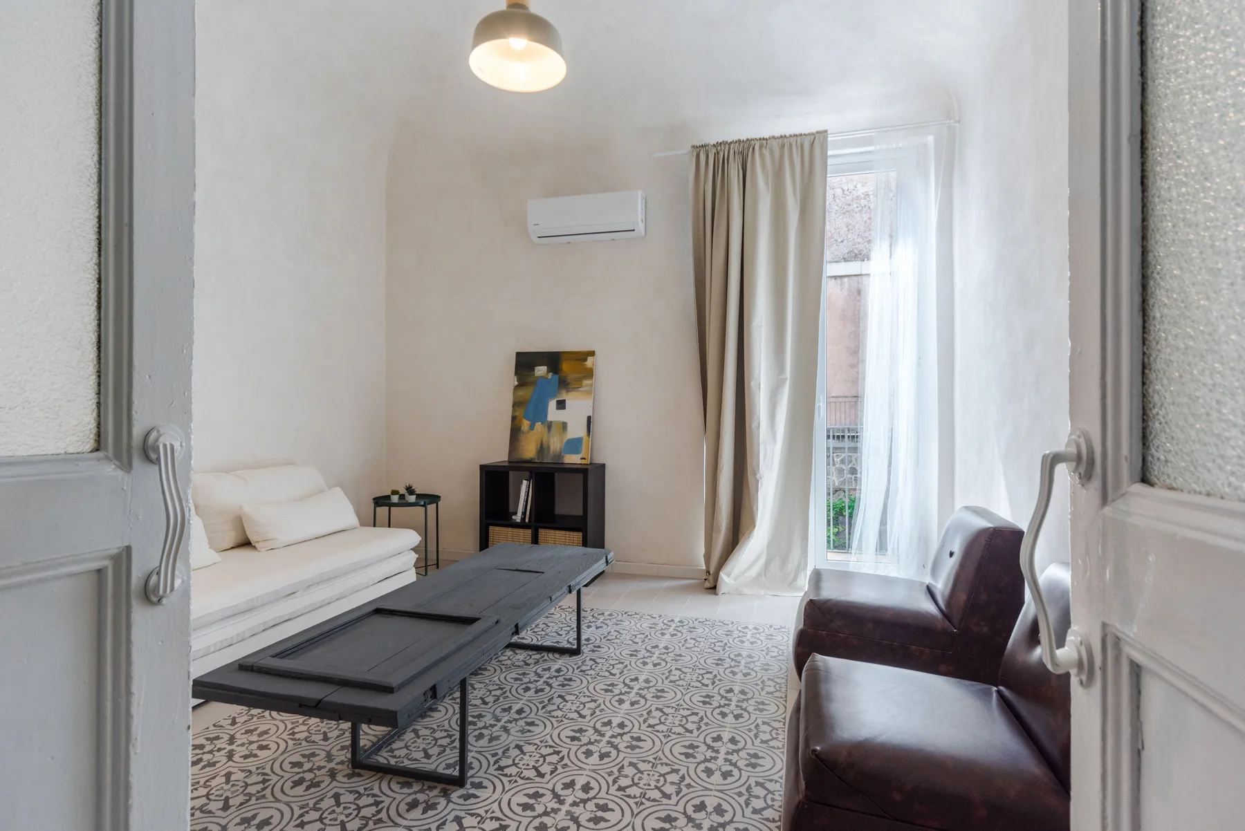 Una sala de estar luminosa con asientos, una mesa baja y una ventana con cortinas.
