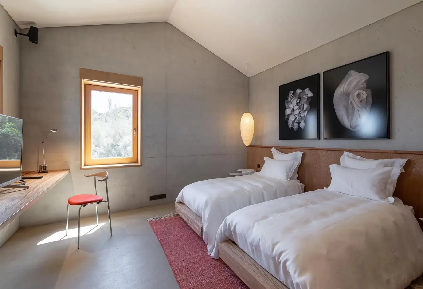 Un dormitorio con dos camas bien hechas, cuadros enmarcados y una ventana.