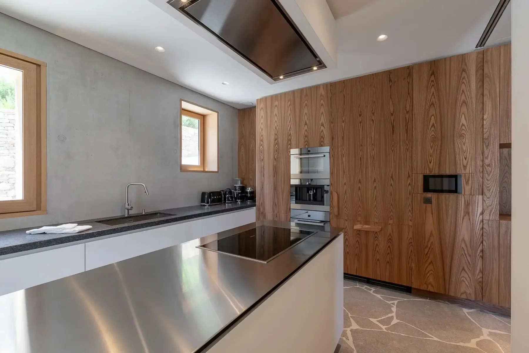Una cocina moderna con una isla de acero inoxidable y gabinetes de madera.