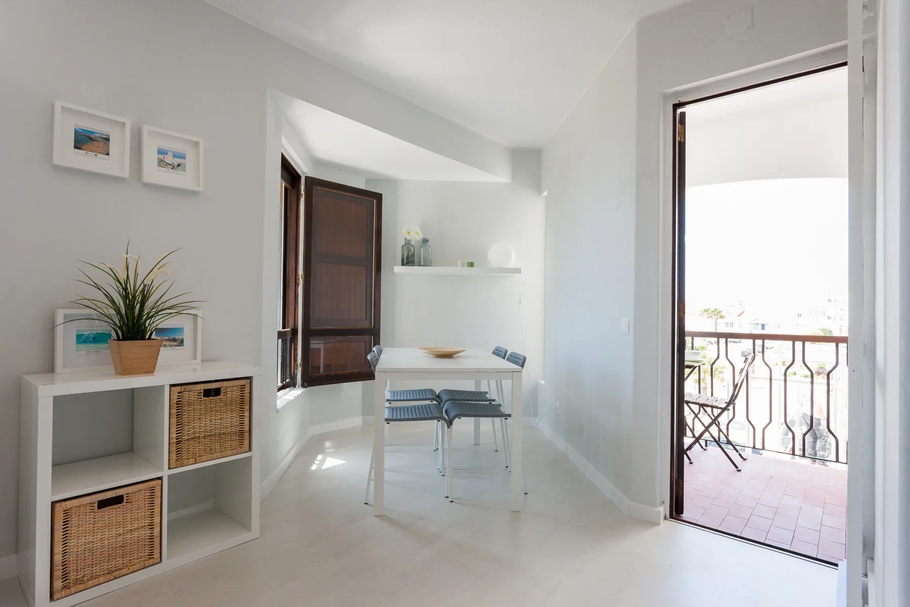 Un luminoso rincón de comedor con mesa y sillas junto a una puerta abierta al balcón.
