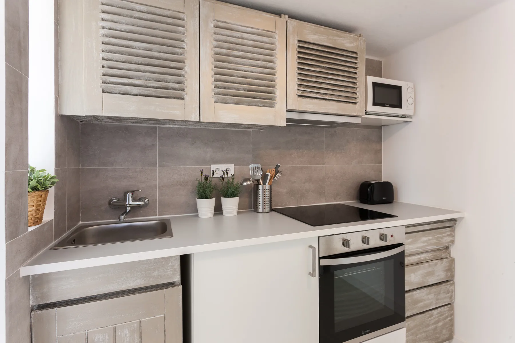 Una cocina compacta con fregadero, placa de cocina y horno empotrado.
