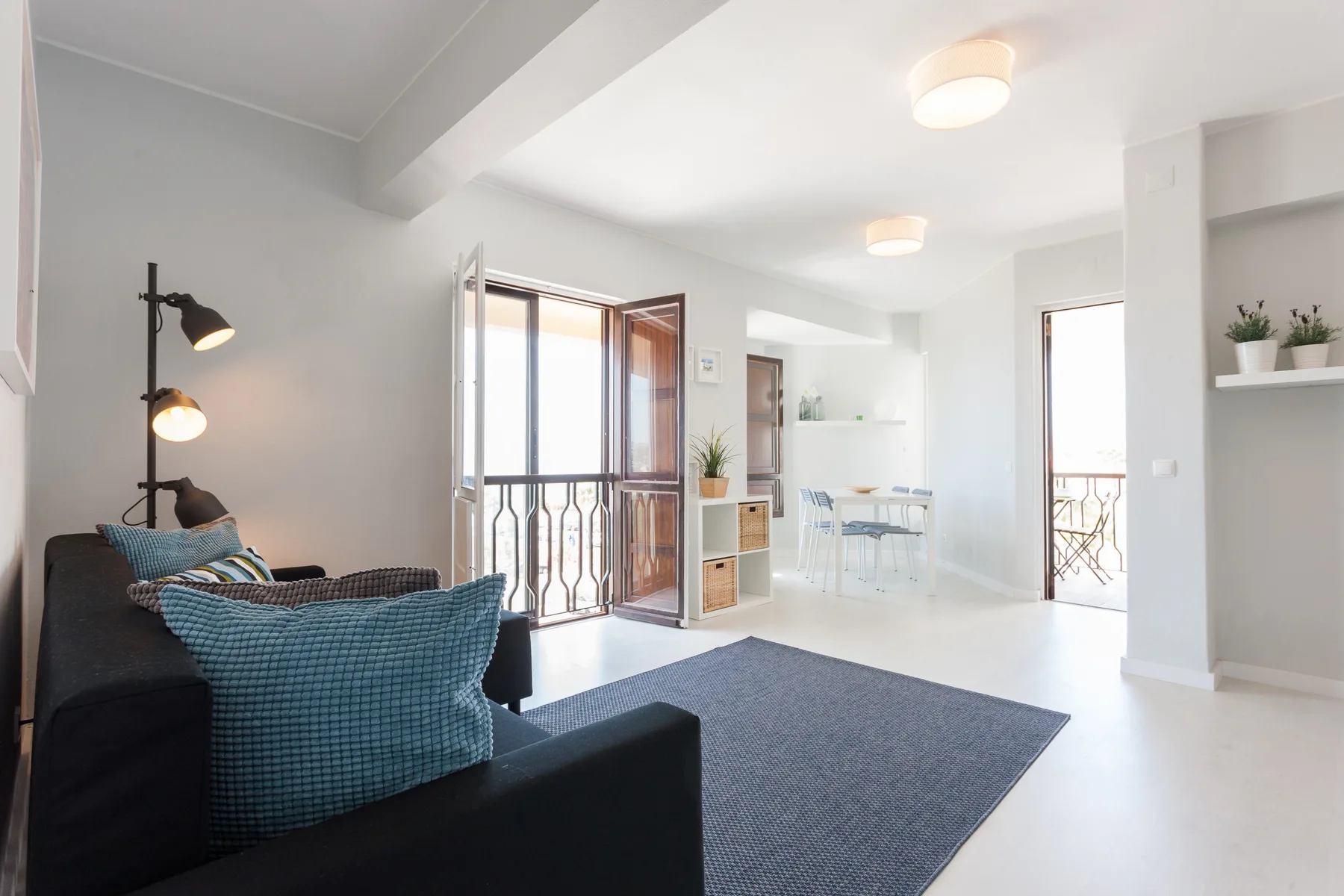 Una luminosa sala de estar y comedor con asientos y una mesa junto a las puertas del balcón.
