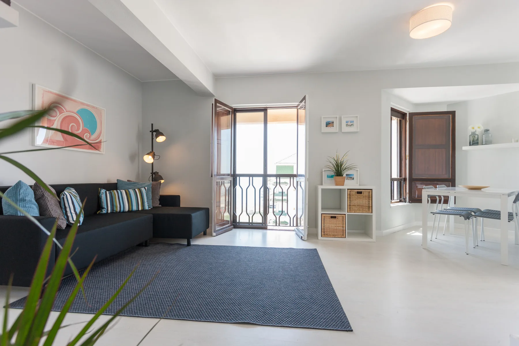 Una sala luminosa da a un balcón, con una zona de estar y un comedor.