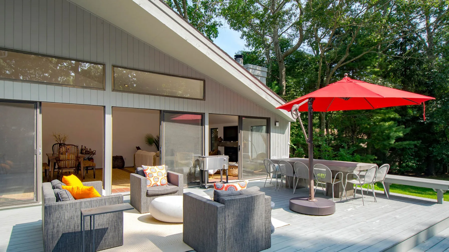 A patio with outdoor seating and a red umbrella beside the house.