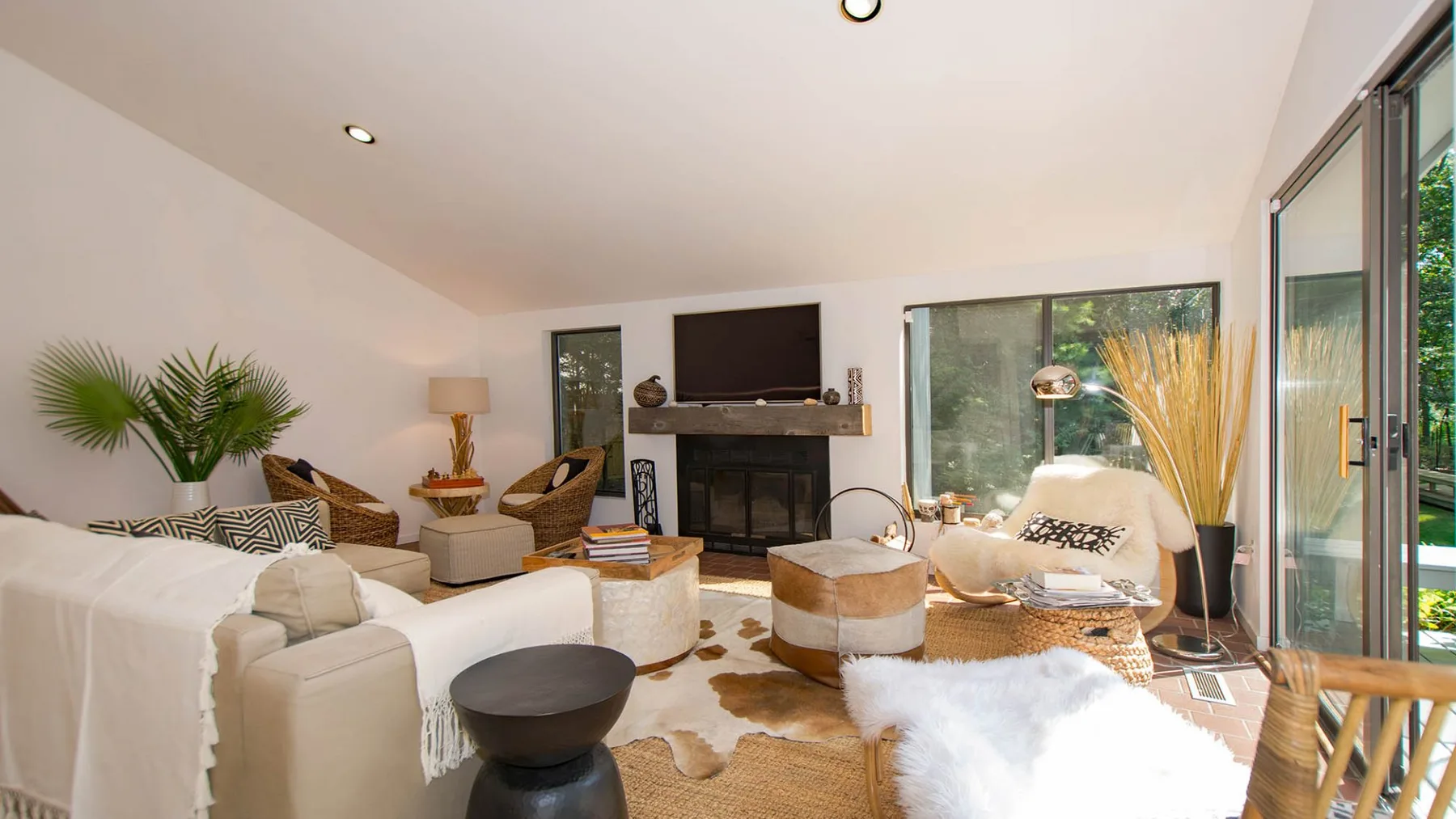 A bright living room with seating arranged around a fireplace and television.