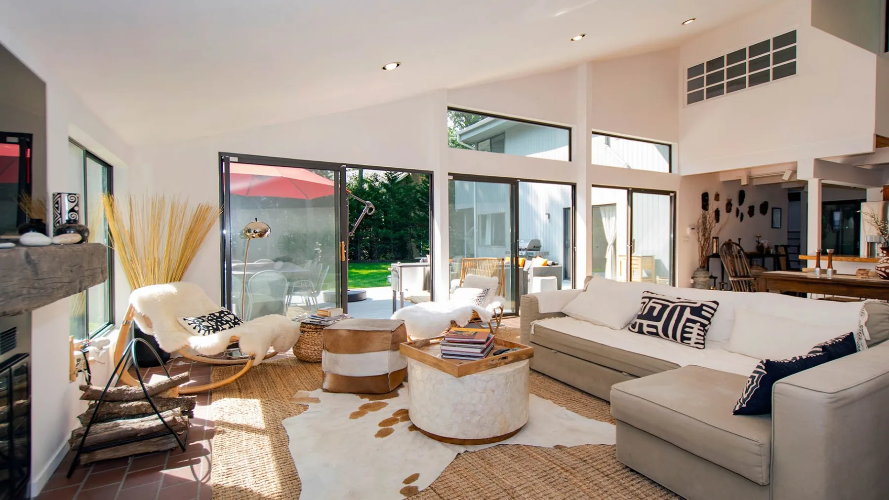 A bright living room with light-colored seating and large glass doors opening to a patio.
