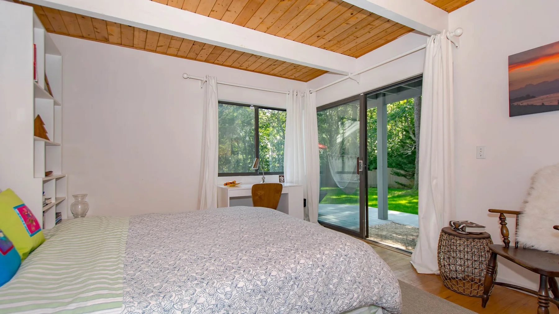 A bedroom with a large bed beside glass doors opening onto a garden.