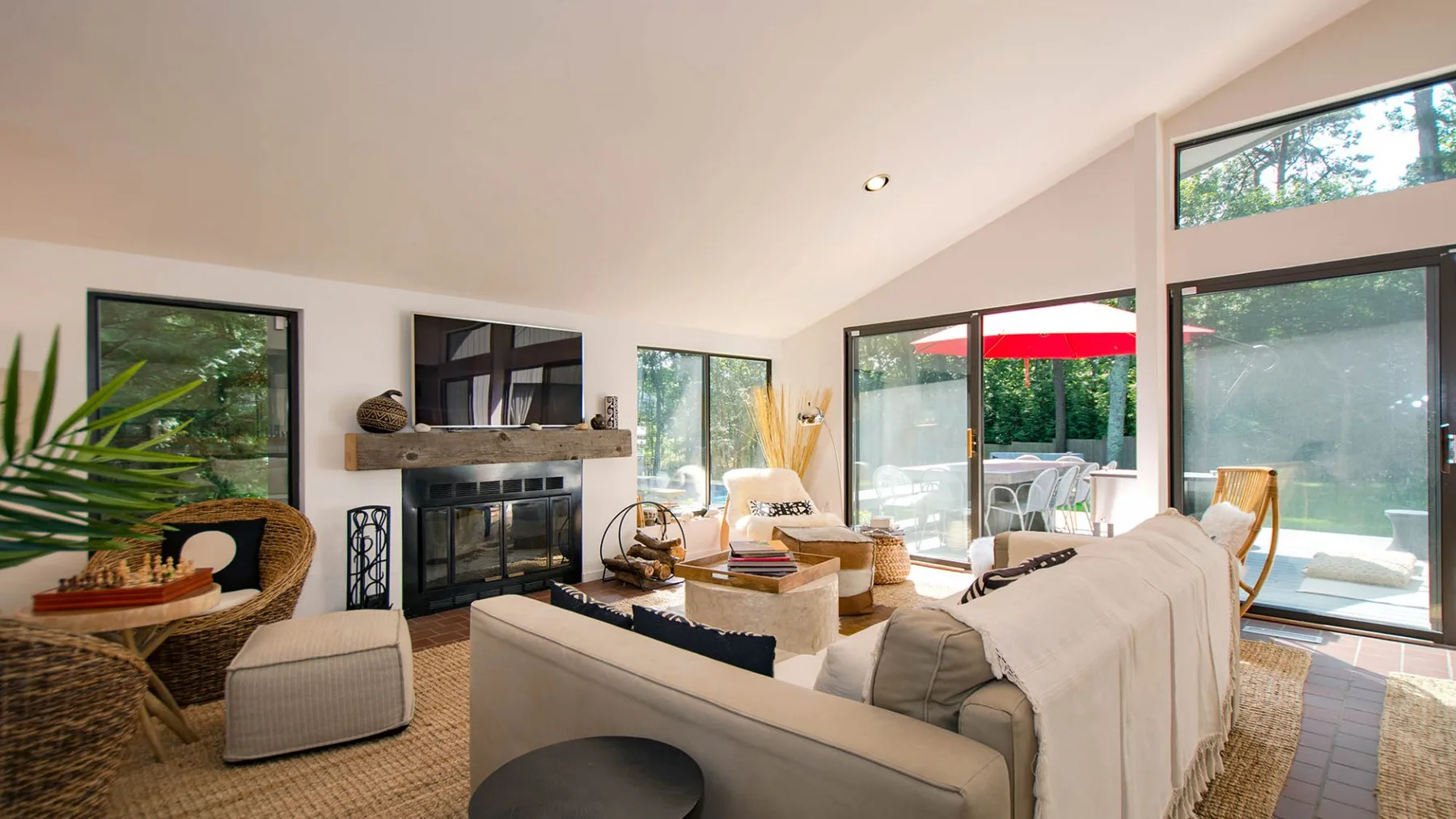 A bright living room with seating arranged around a fireplace and large windows.