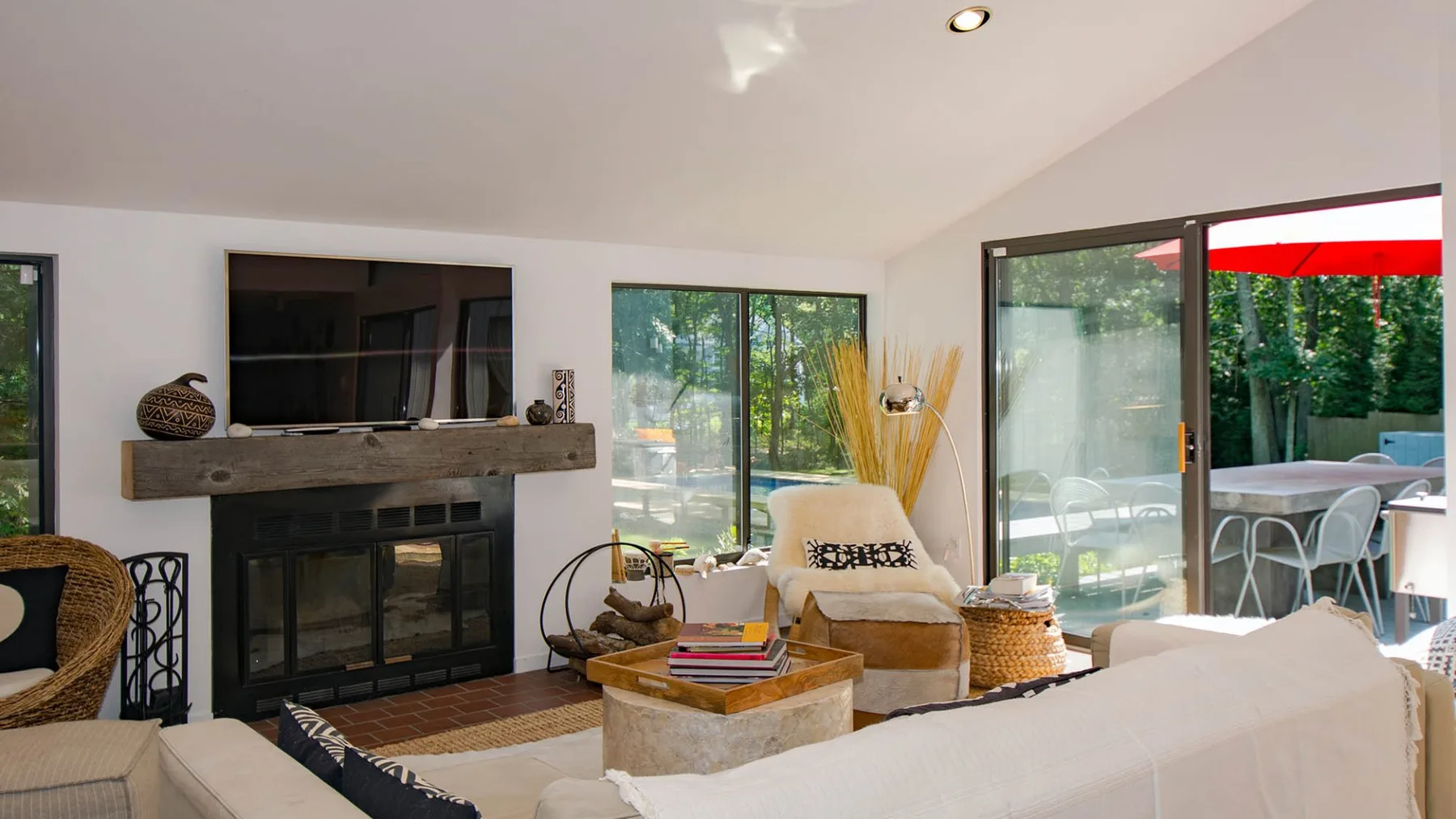 A bright living room with a fireplace, seating, and large glass doors opening to a patio.