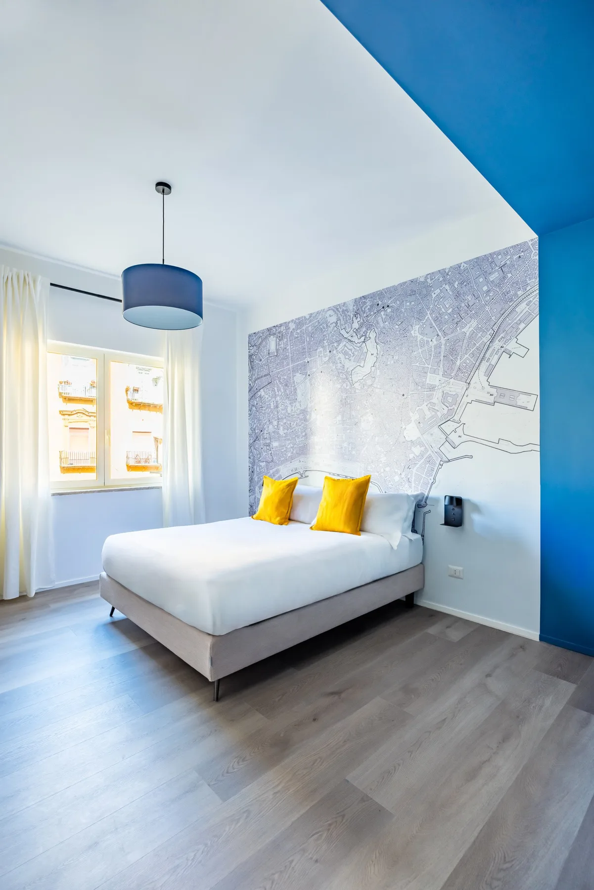 A bright bedroom with a bed and yellow accent pillows.