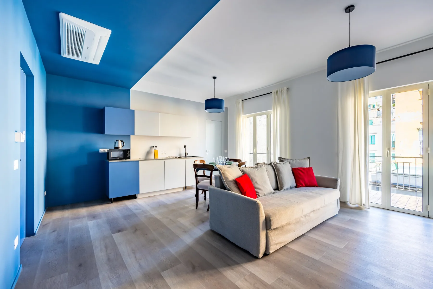 An open-plan living room and kitchen with blue cabinetry and a sofa.