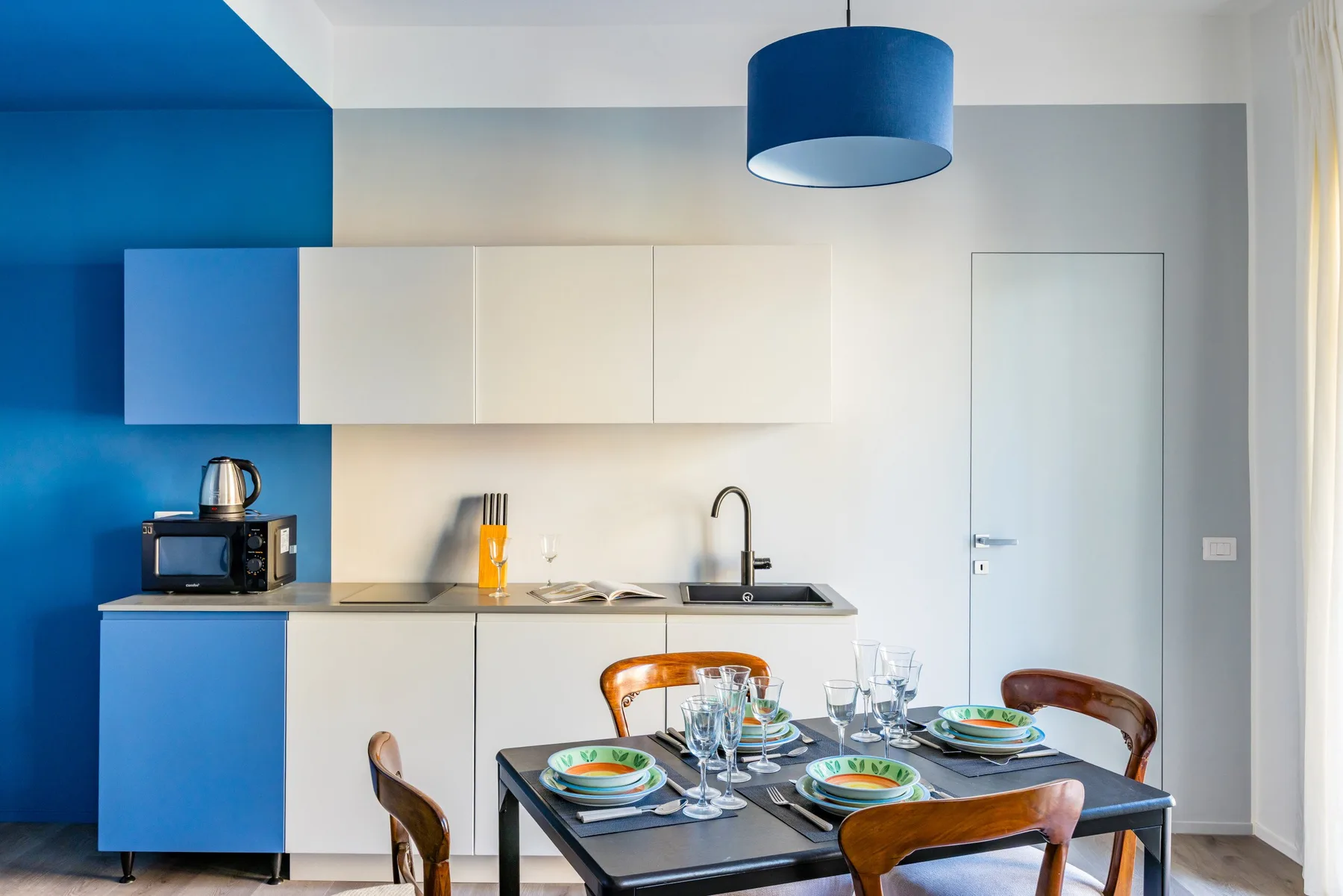 A modern kitchen with white cabinets and a dining table set with dishes.