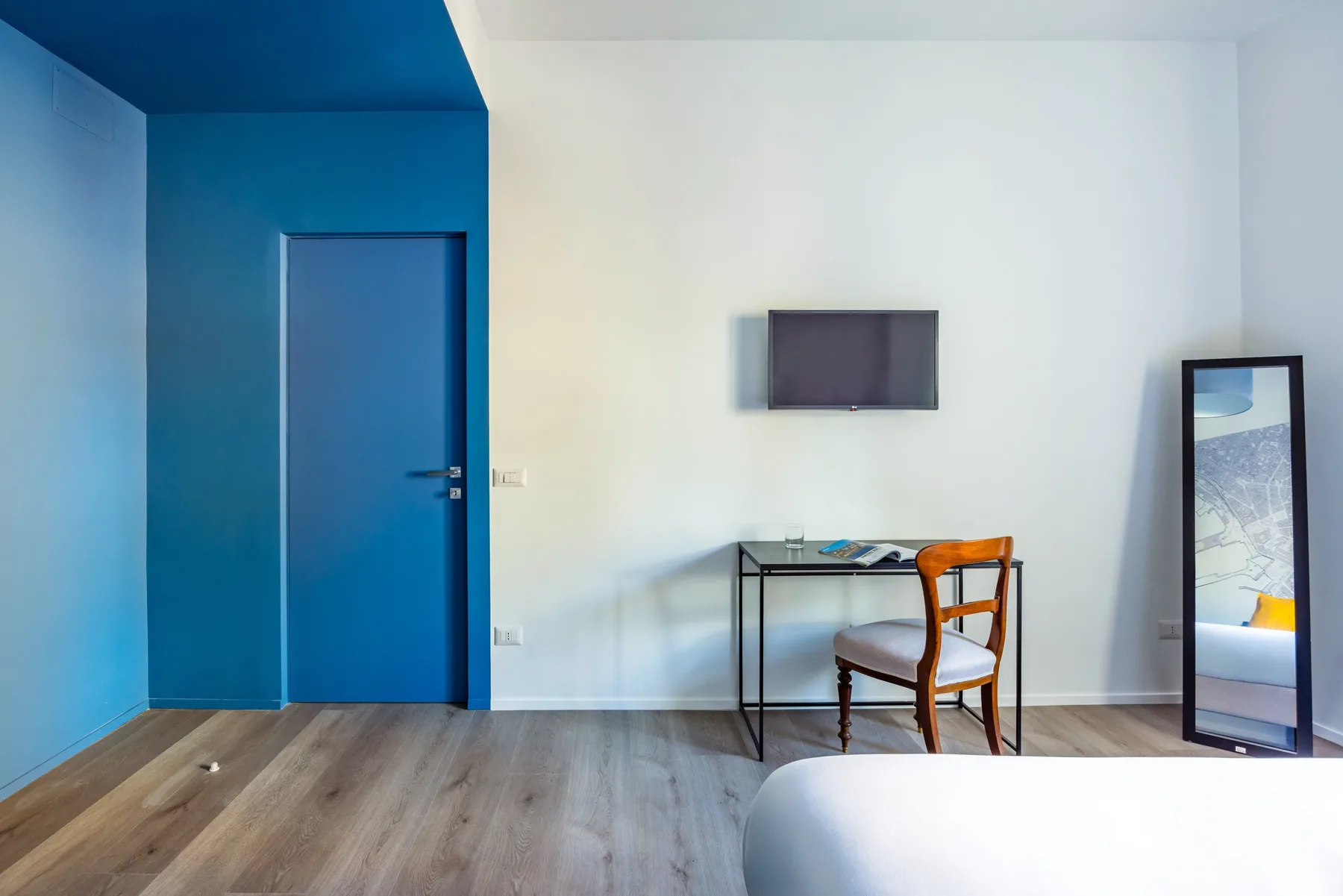 A simple room with a desk, chair, and wall-mounted television.