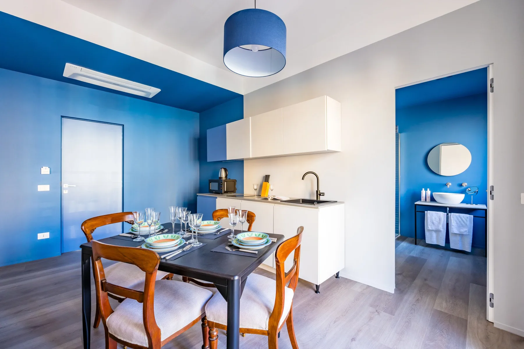 A dining area with a set table beside a compact kitchen.