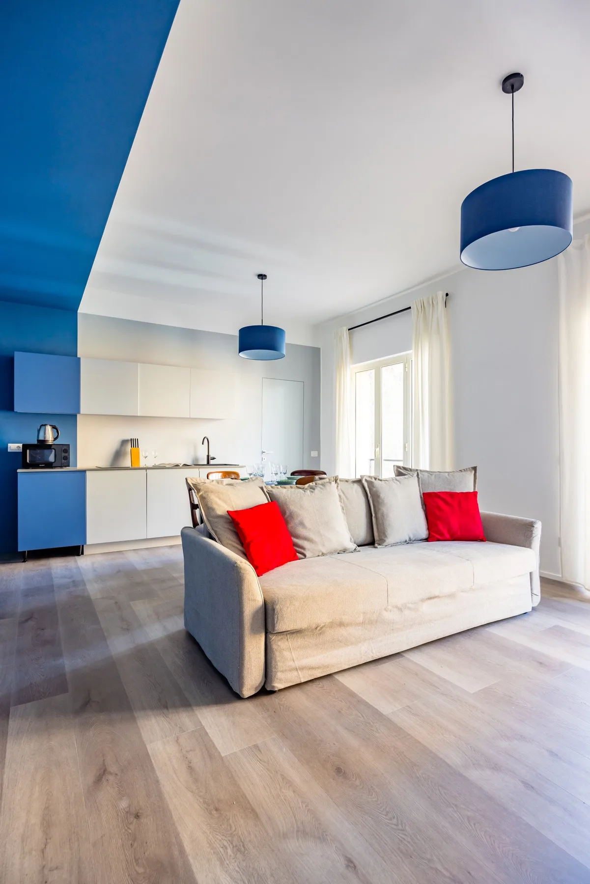 A bright living room with a light-colored sofa and an open kitchen.