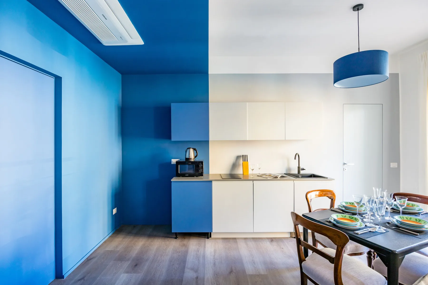A modern kitchen and dining area with blue walls and a set table.
