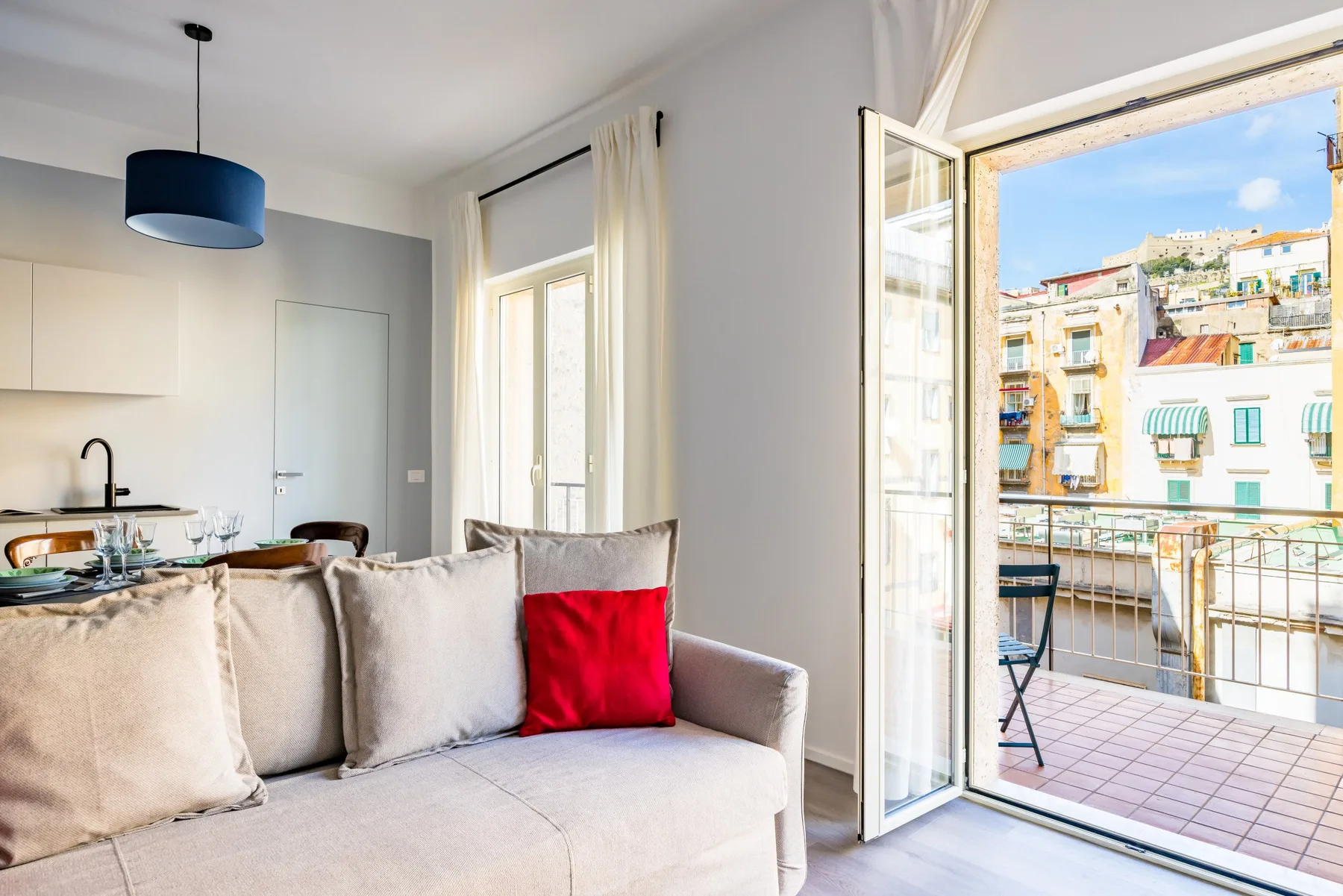 A bright living room opens onto a balcony through wide glass doors.