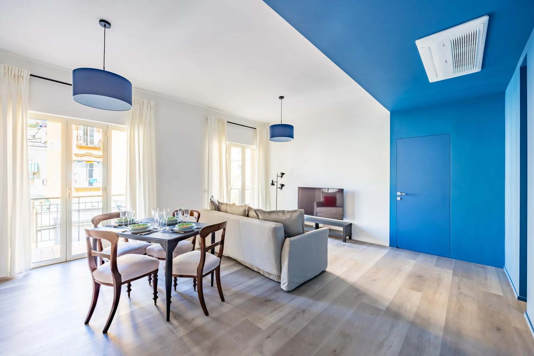 A bright living and dining area with a table beside large windows.