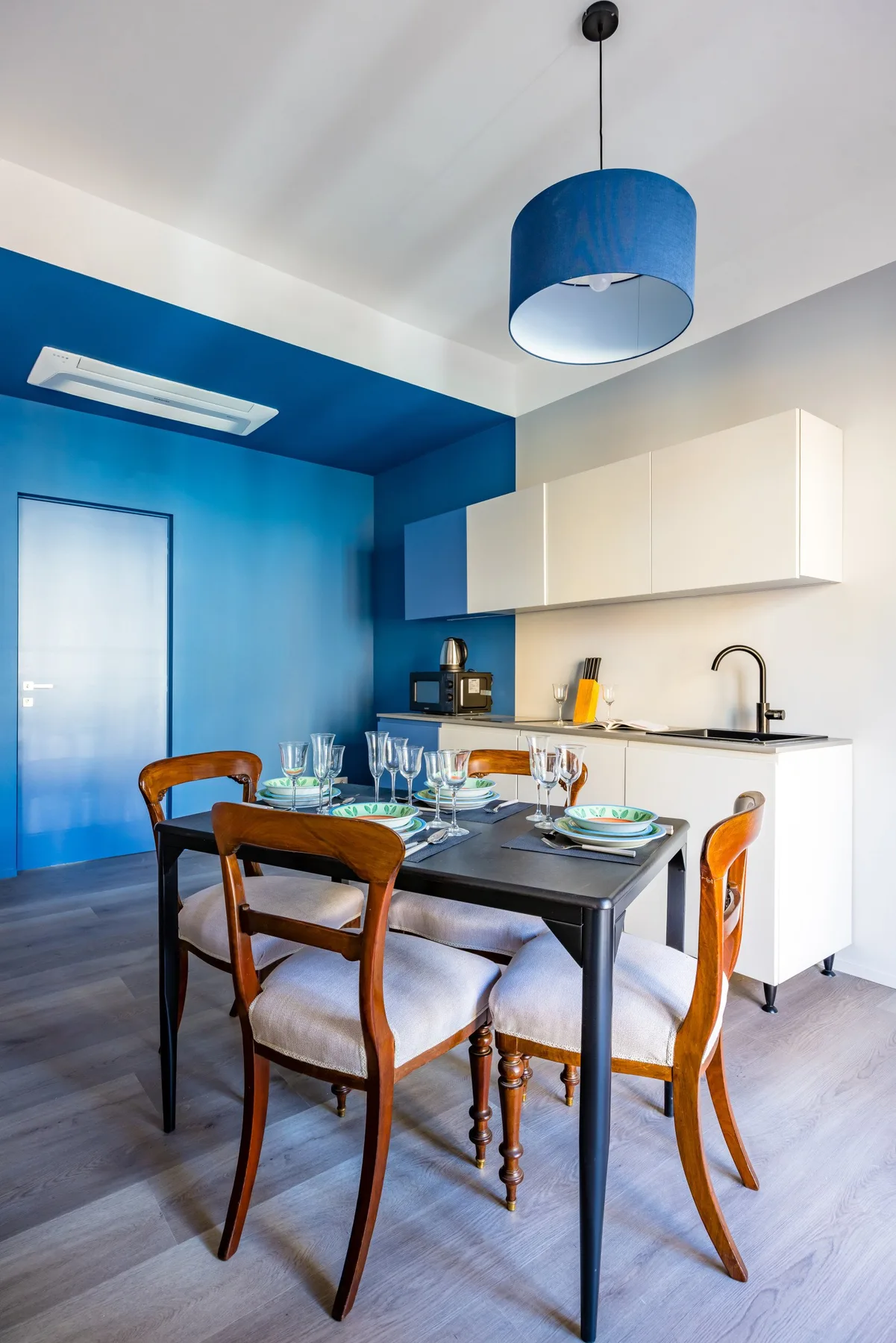A dining area with a table and chairs beside a compact kitchen.